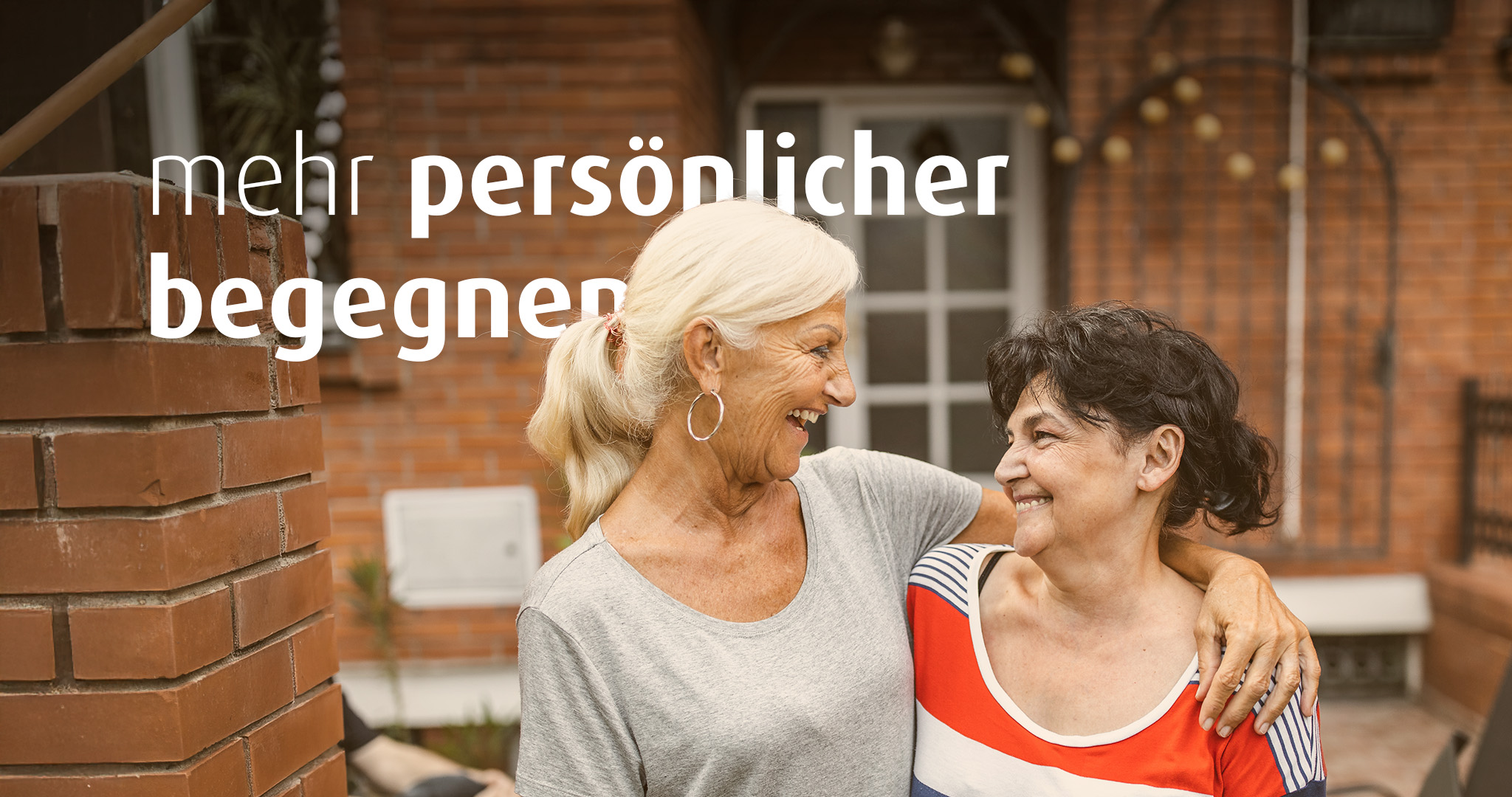 Zwei Frauen stehen nebeneinander und halten sich im Arm. Auf dem Bild steht der Text "mehr persönlicher begegnen".