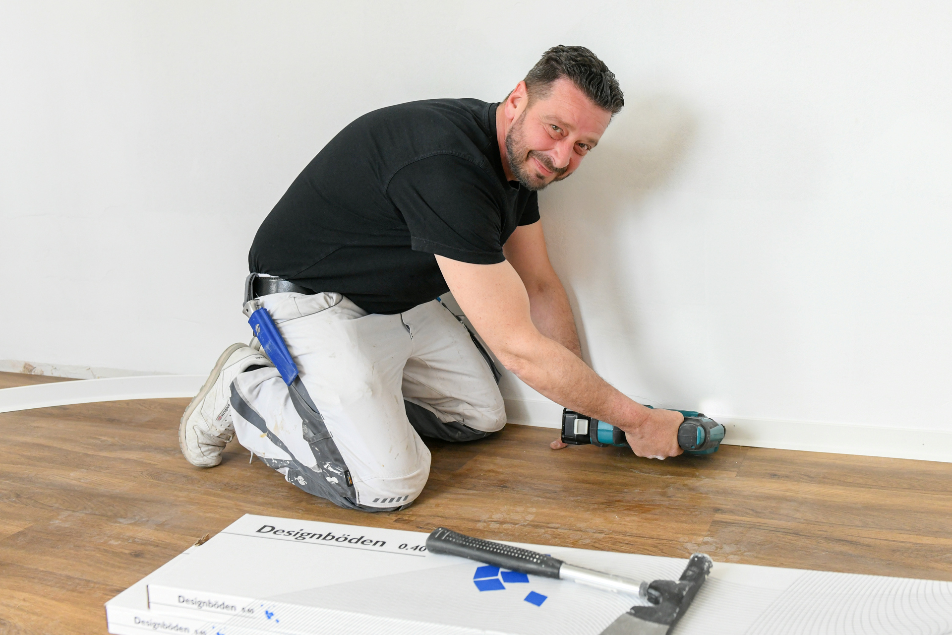 Handwerker montiert eine Fußbodenleiste.