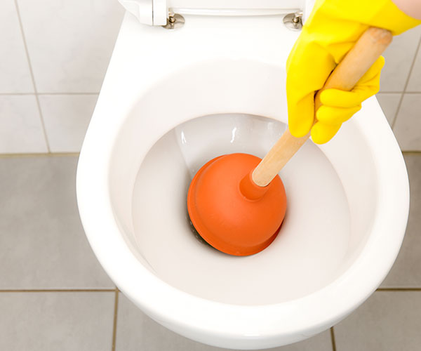 Toilette wird mit Saugglocke gereinigt.