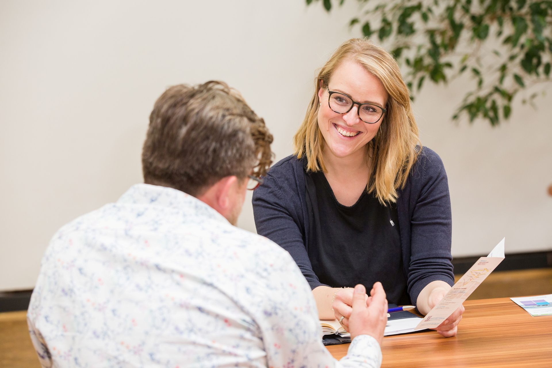 Eine Frau und ein Mann im Gespräch. Sie sitzen an einem Tisch.