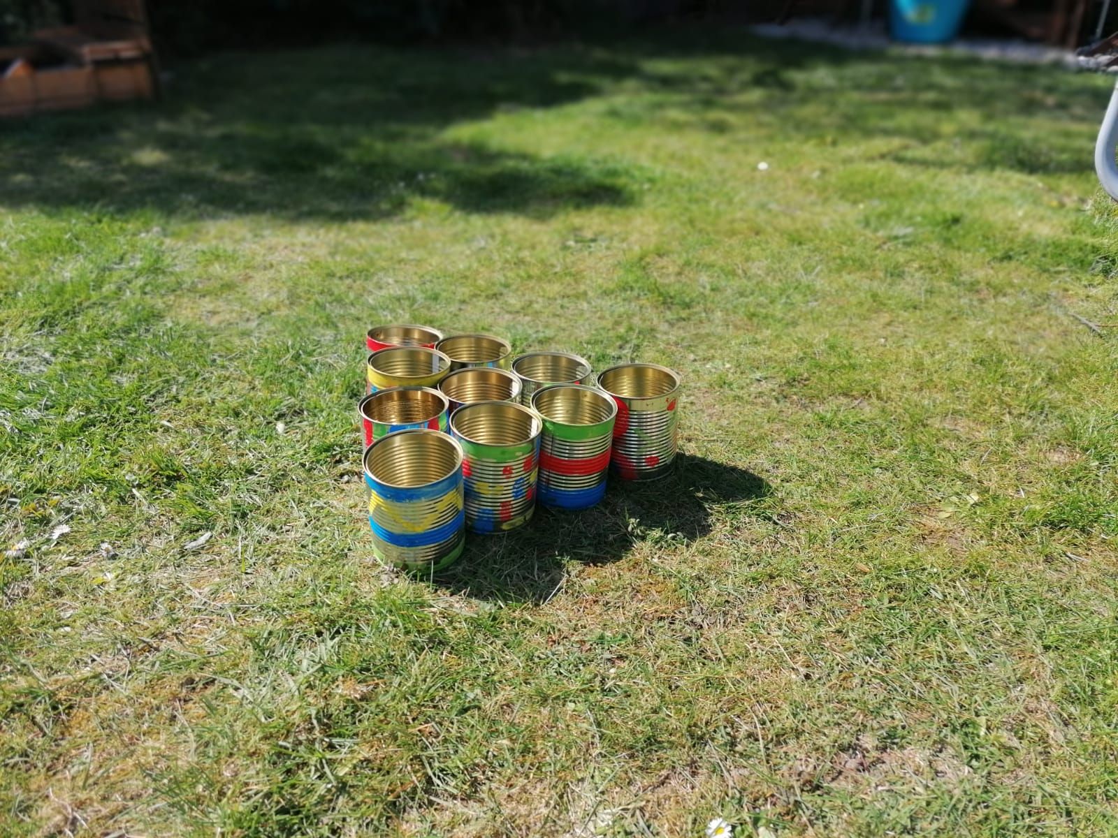 Bunte Dosen stehen auf einer Wiese. Sind sind in einem Dreieck angeordnet.