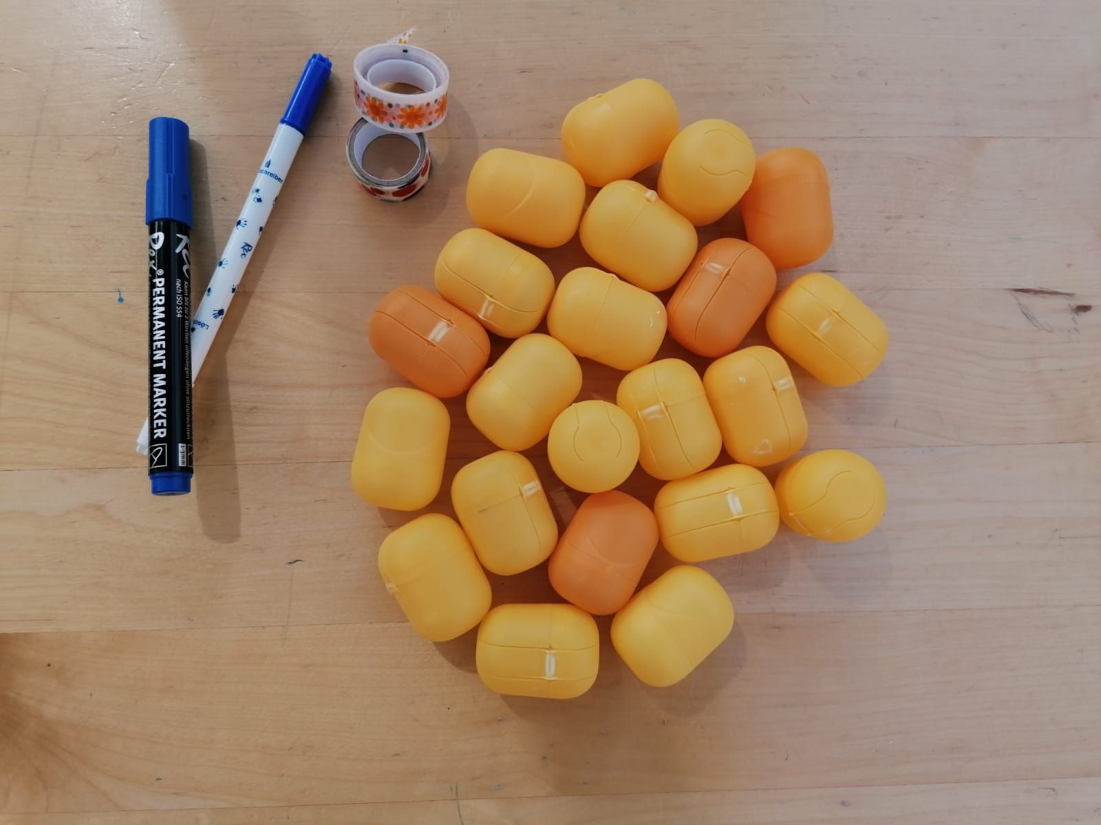 Kleine, gelbe Verpackungen und Stifte und Klebeband liegen auf einem Tisch.