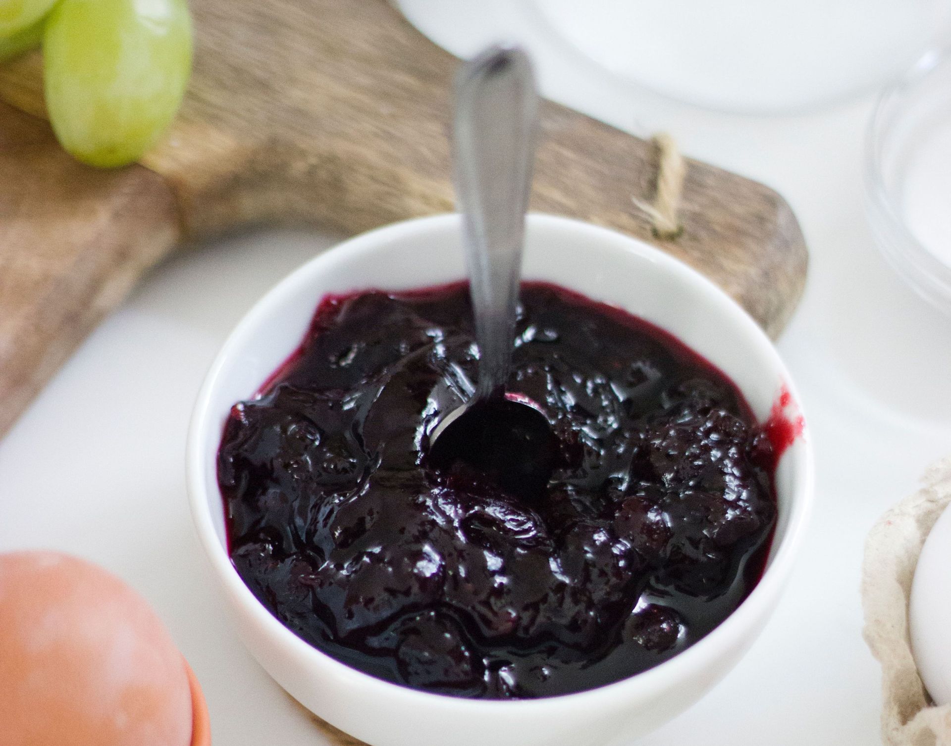 Rote Marmelade in einem Schälchen mit Löffel.