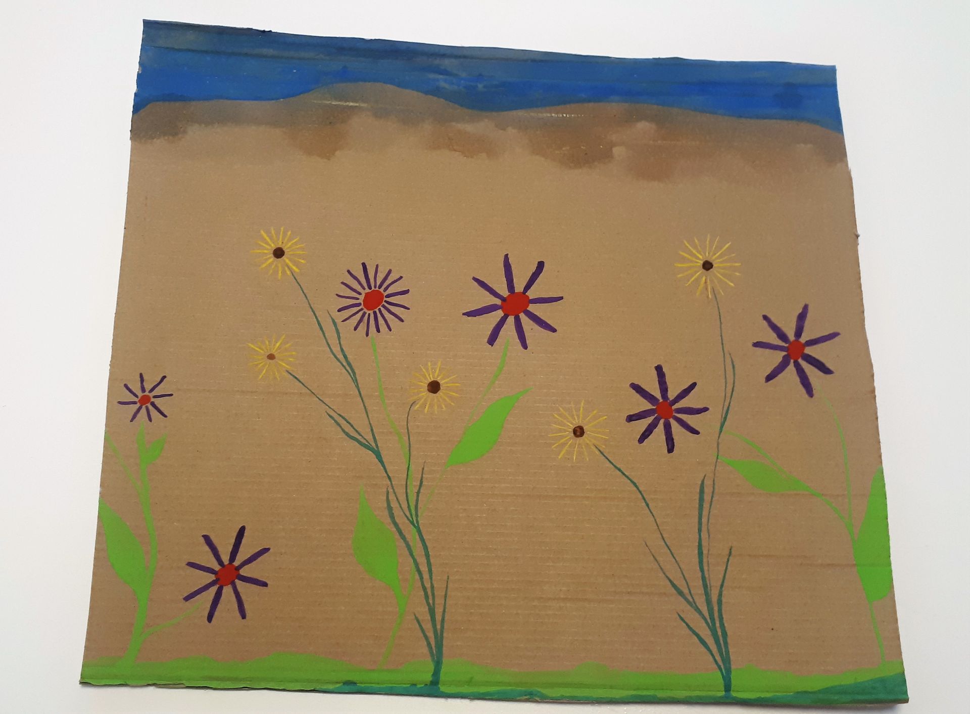 Ein Stück Pappe ist mit Blumen bemalt.