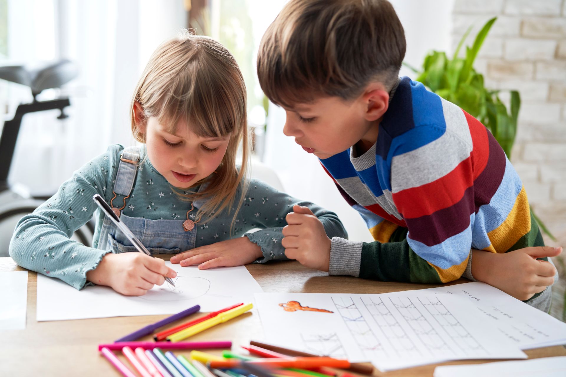 Junge und Mädchen sitzen zusammen am Schreibtisch und malen.