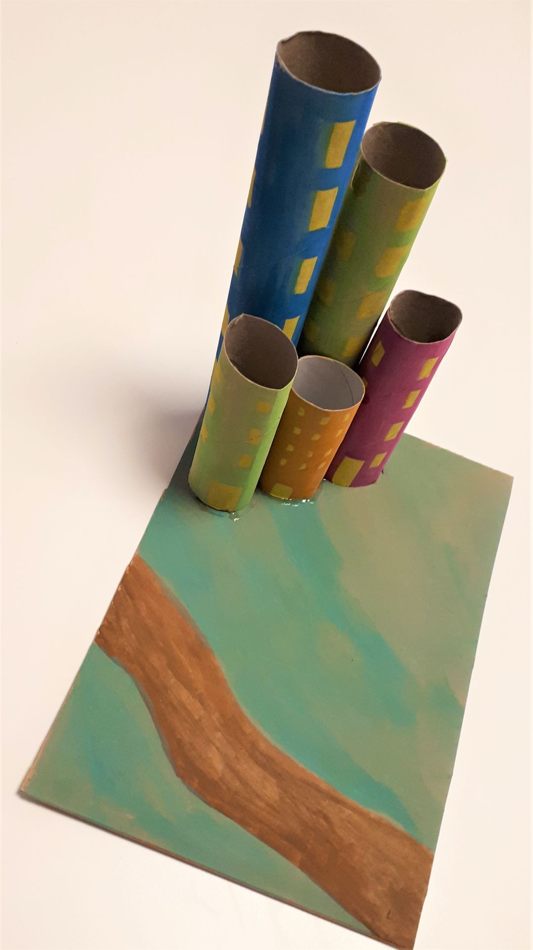 Bemalte Papprollen sind auf ein Stück bemalte Pappe geklebt.