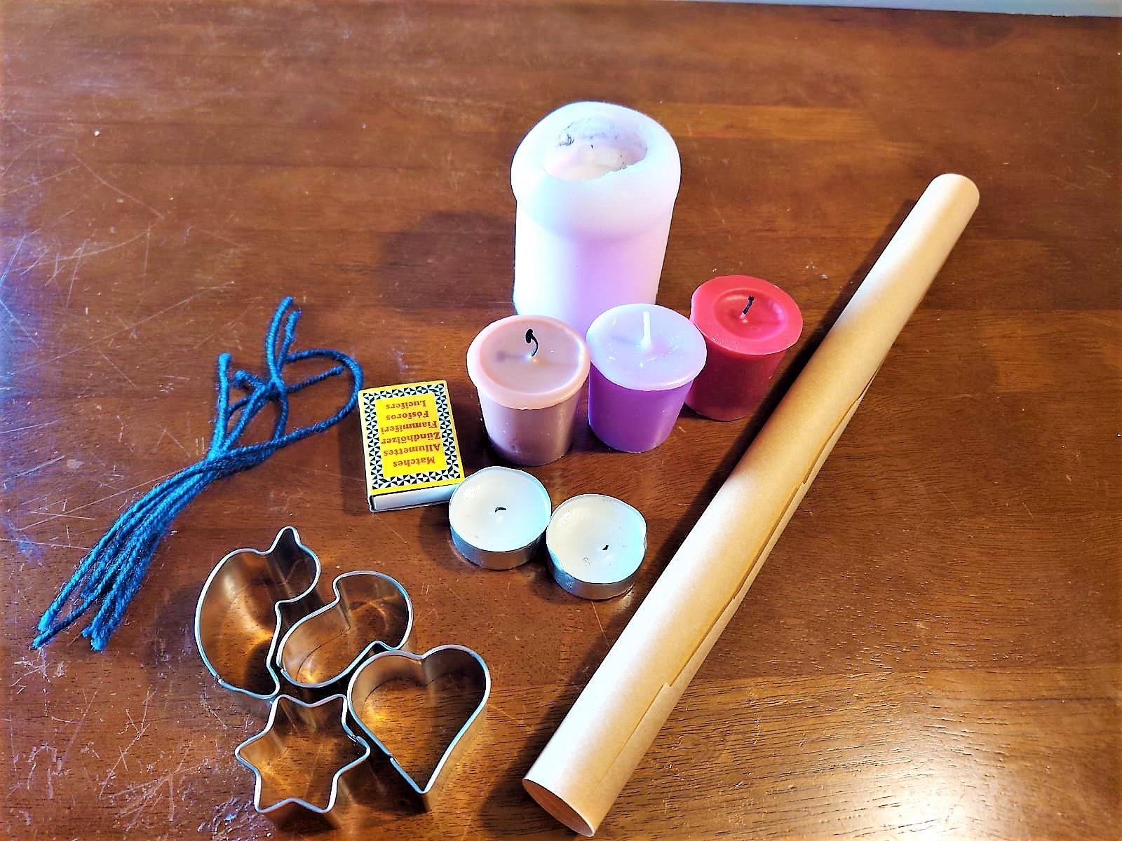 Backpapier, Kerzen, Wolle und Ausstechformen liegen auf einem Tisch.