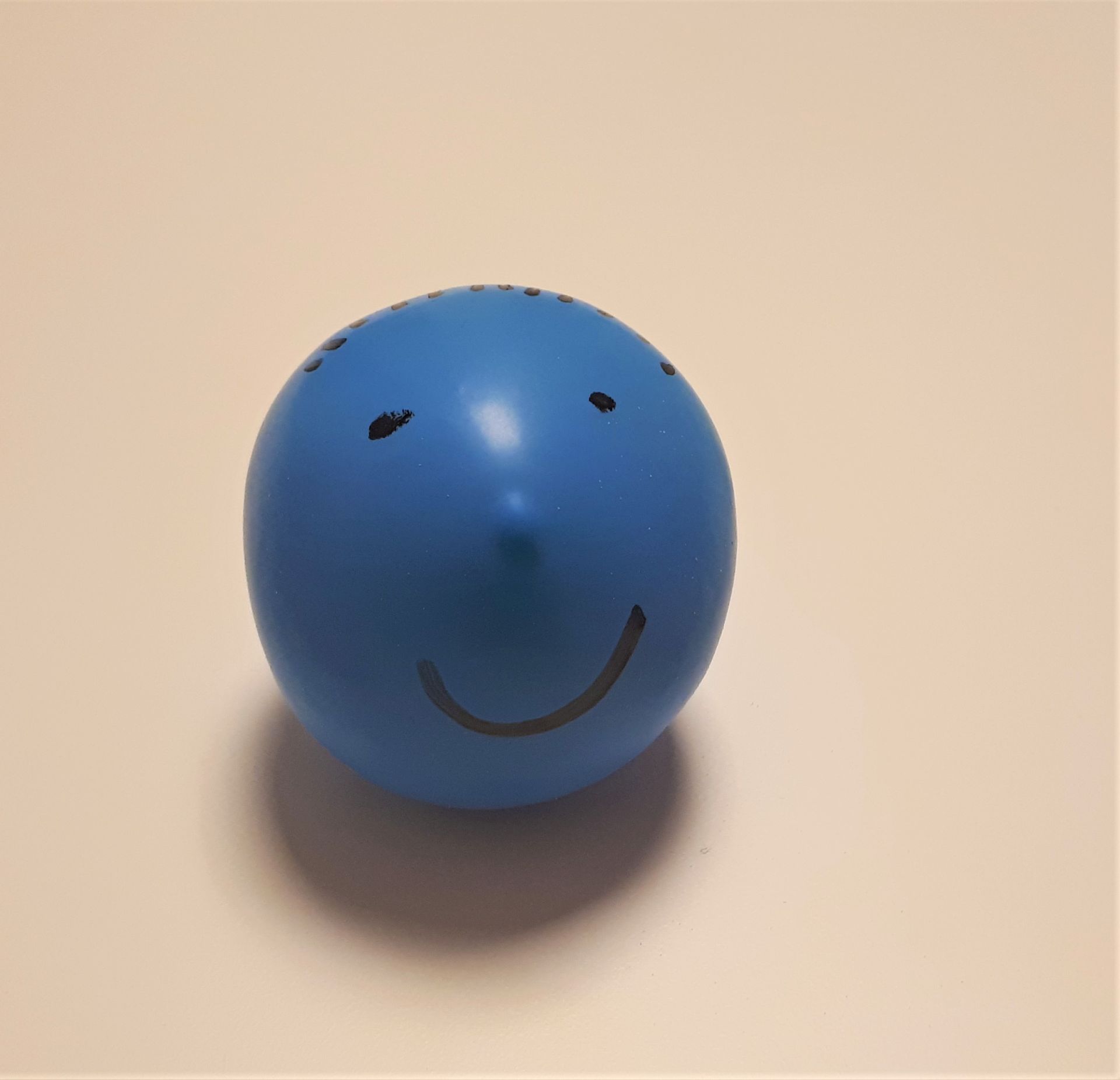 Blauer Luftballon mit aufgemaltem Gesicht.