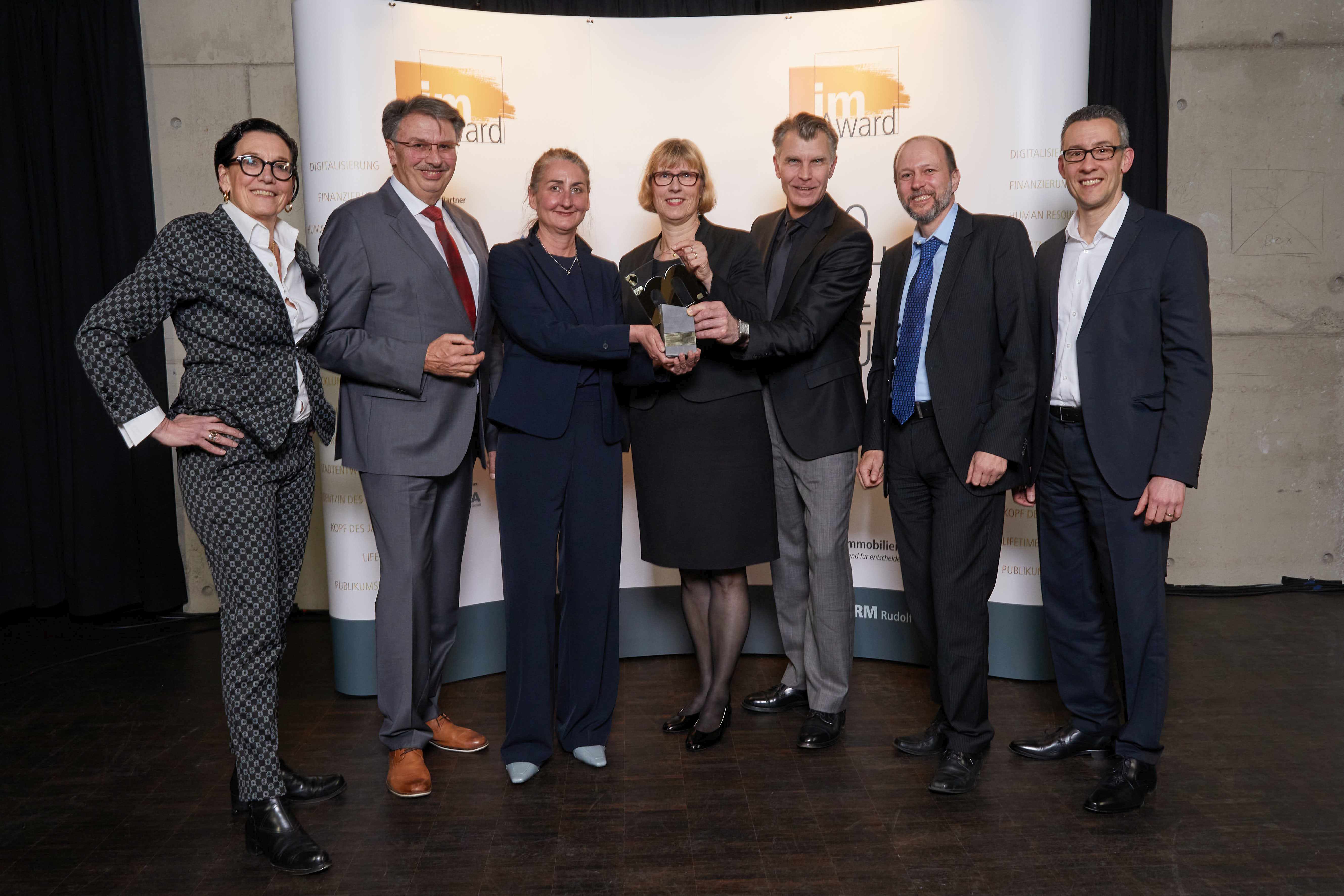 Glückliche Preisträger des im-Award 2024: v.l.n.r. Marion Schmitz-Stadtfeld (NHW), Manfred Ockel (Bgm. Kelsterbach), Alexa von Wedel (NHW), Monika Fontaine-Kretschmer (GFin NHW), Robert Lotz (NHW), Helge Bitzer (NHW), Thomas Türkis (NHW). 