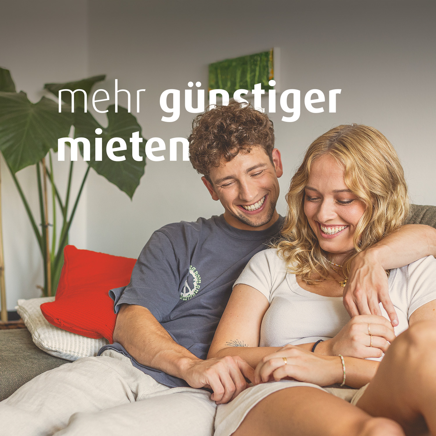 Ein junger Mann und eine junge Frau sitzen gemeinsam auf dem Sofa. Der Mann hat den Arm um die Frau gelegt. Auf dem Bild steht der Text "mehr günstiger mieten".