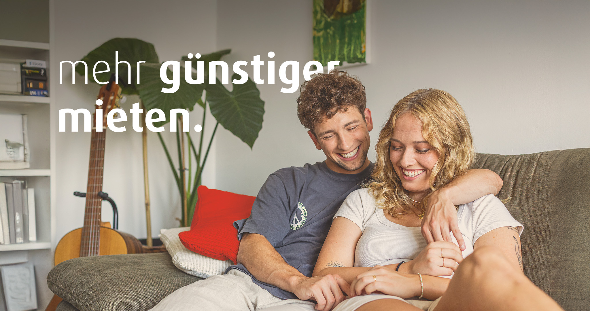Ein junger Mann und eine junge Frau sitzen gemeinsam auf dem Sofa. Der Mann hat den Arm um die Frau gelegt. Auf dem Bild steht der Text "mehr günstiger mieten".