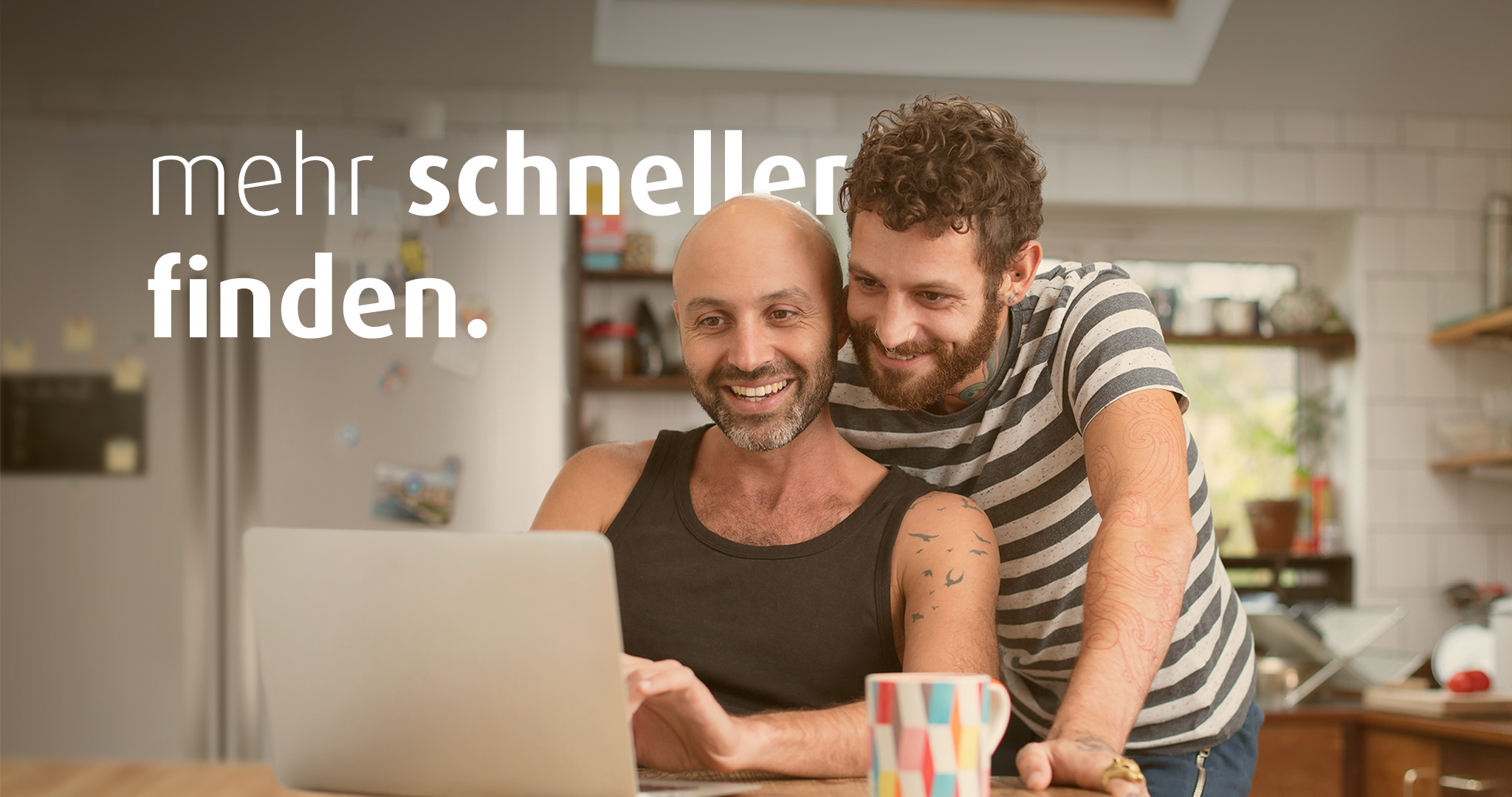 Zwei Männer sind in der Küche und schauen gemeinsam auf einen Laptop. Auf dem Bild steht "mehr schneller finden".