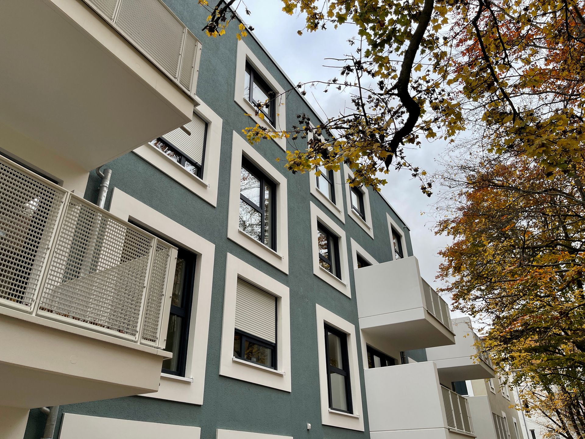 Mehrfamilienhaus mit Baum und Balkonen