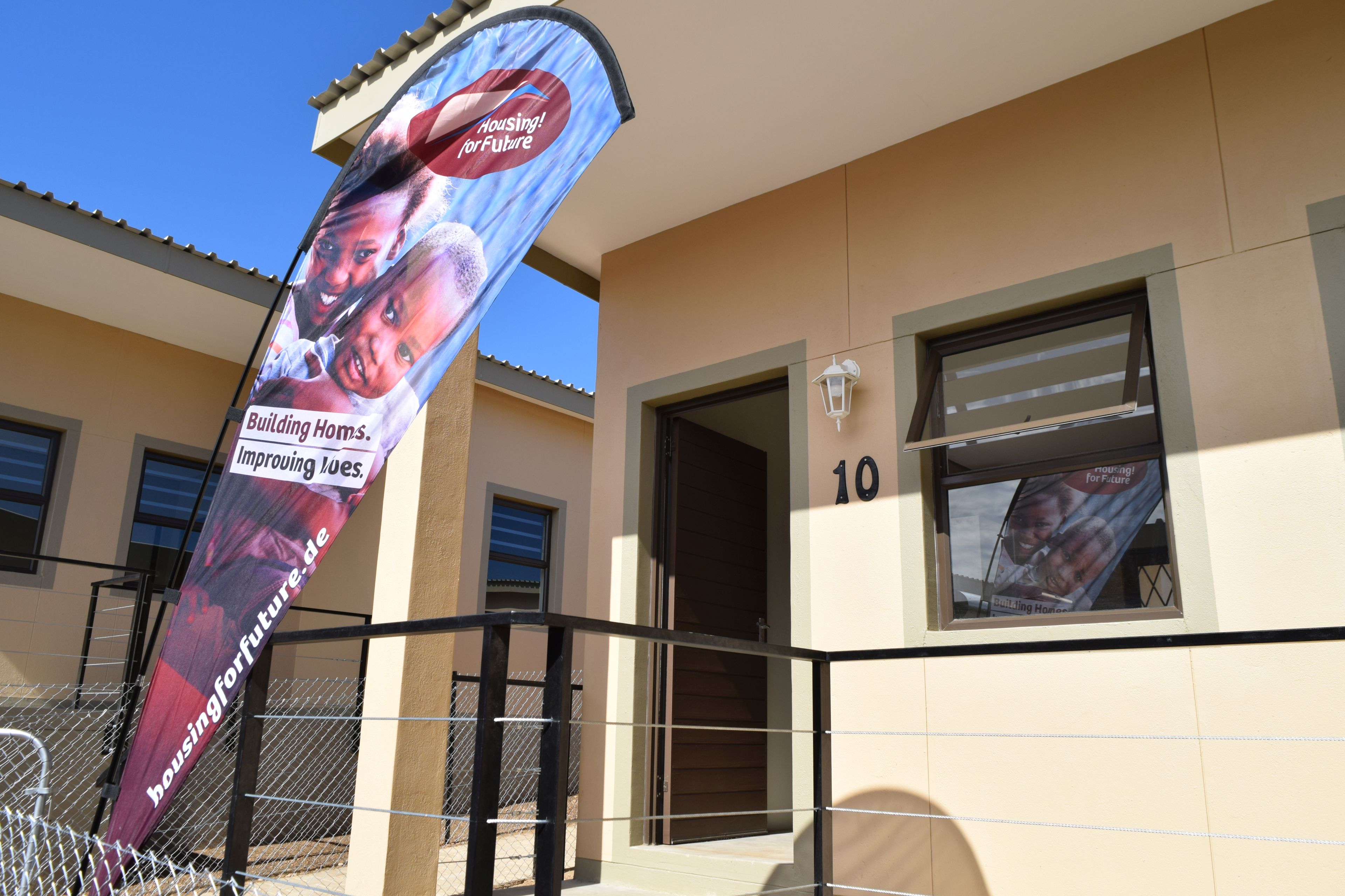 Beach Flag von Housing! for Future vor einem der neuen Häuser