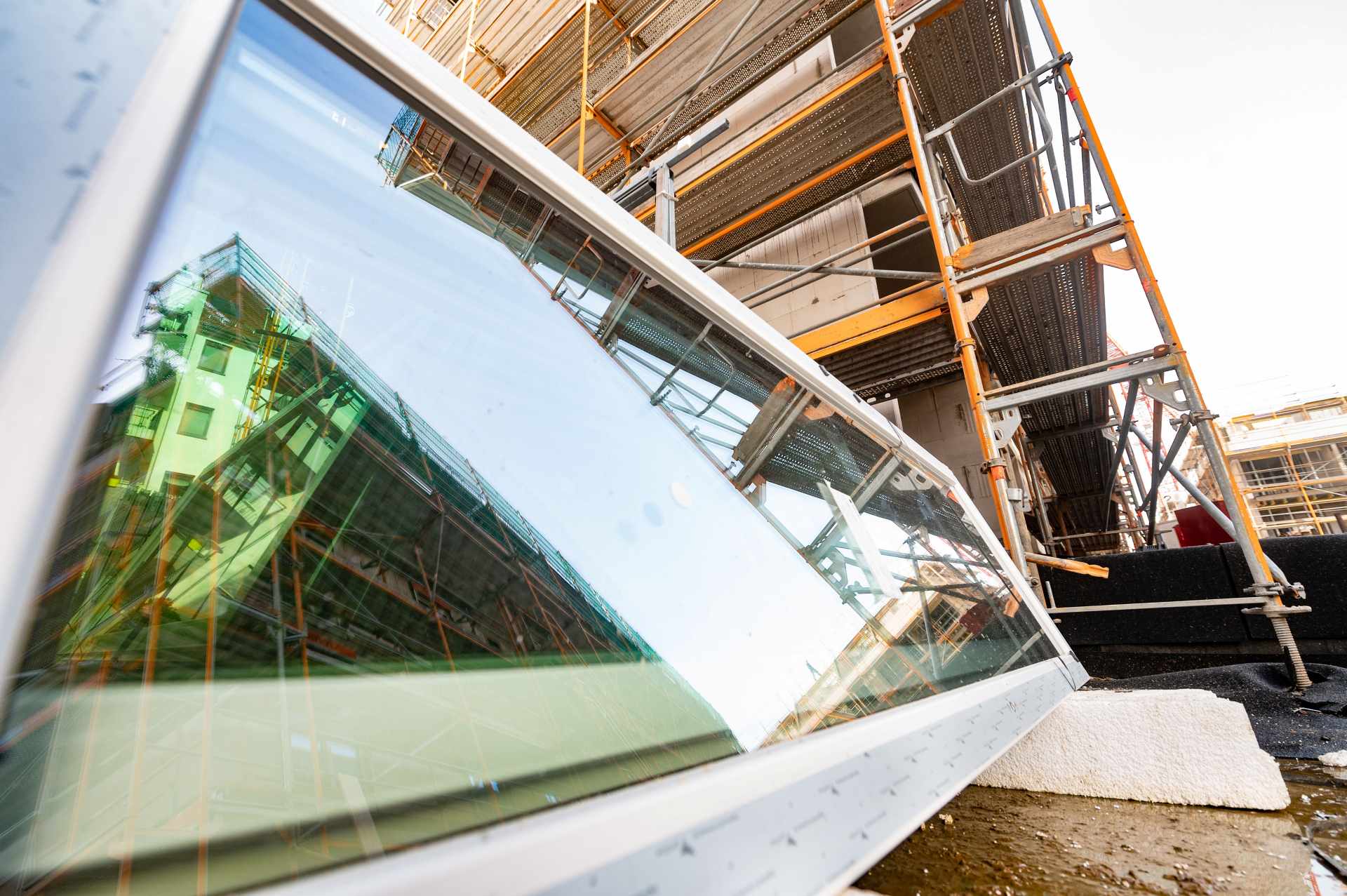 Neues Fenster vor einem Gerüst auf einer Baustelle.