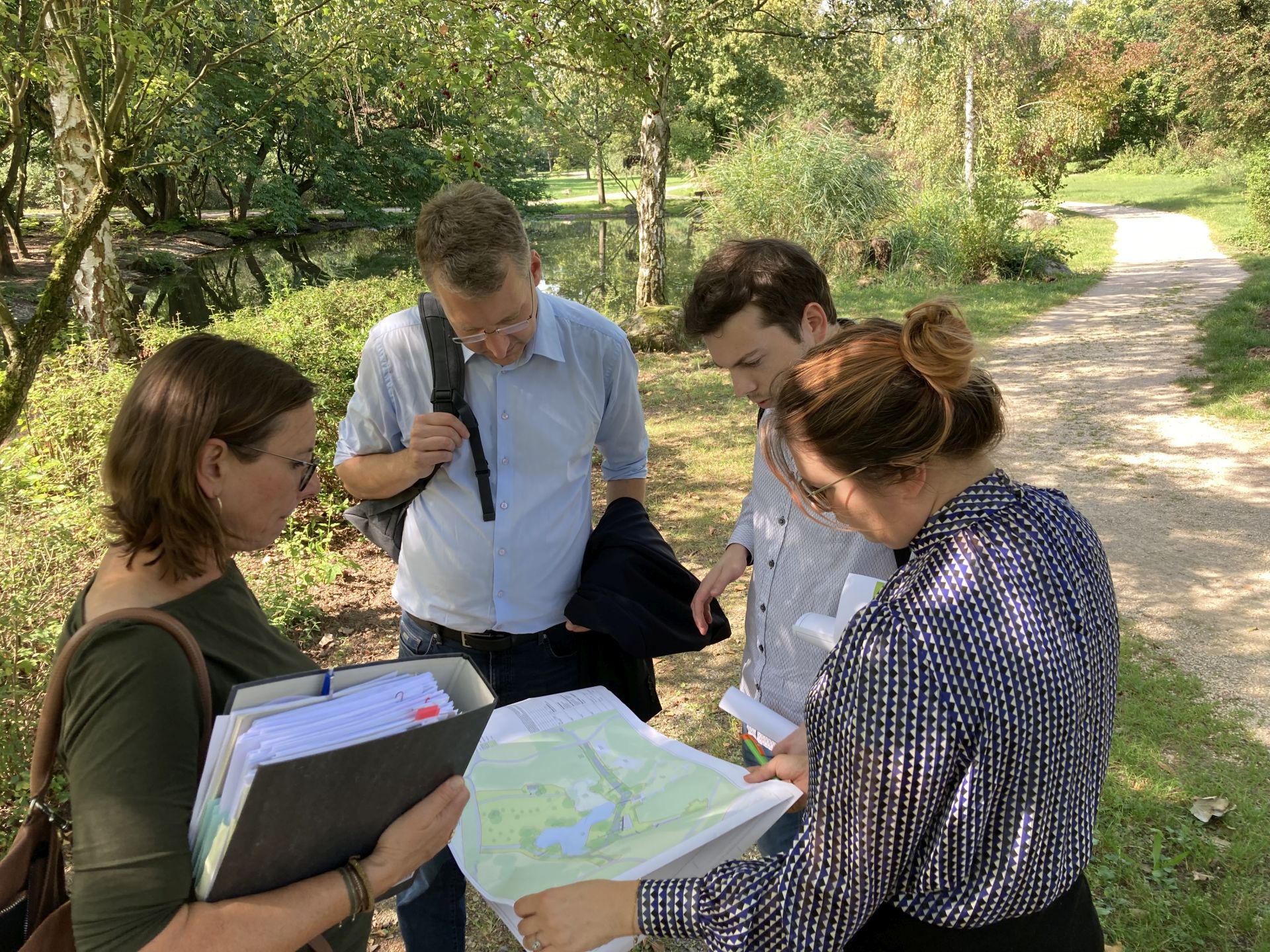 Vier Personen im Grünen mit Unterlagen: Heiko Körner und Benedikt Sauer vom Land Hessen mit Bettina Weise (Stadt Kelsterbach) und Malaika Rahm (ProjektStadt)