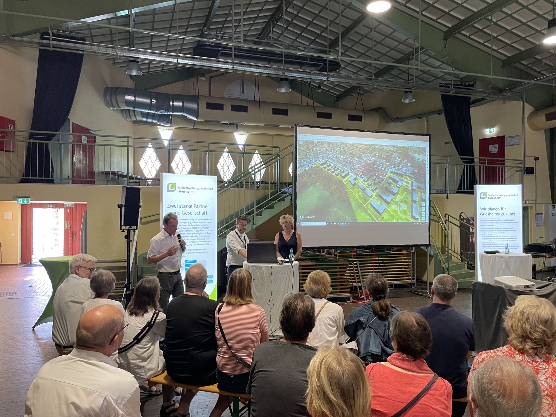 Die Verantwortlichen erläutern den Zuhörern vor einer Leinwand und mit Mikrofon, wies es mit dem Griesheimer Anger weitergeht.