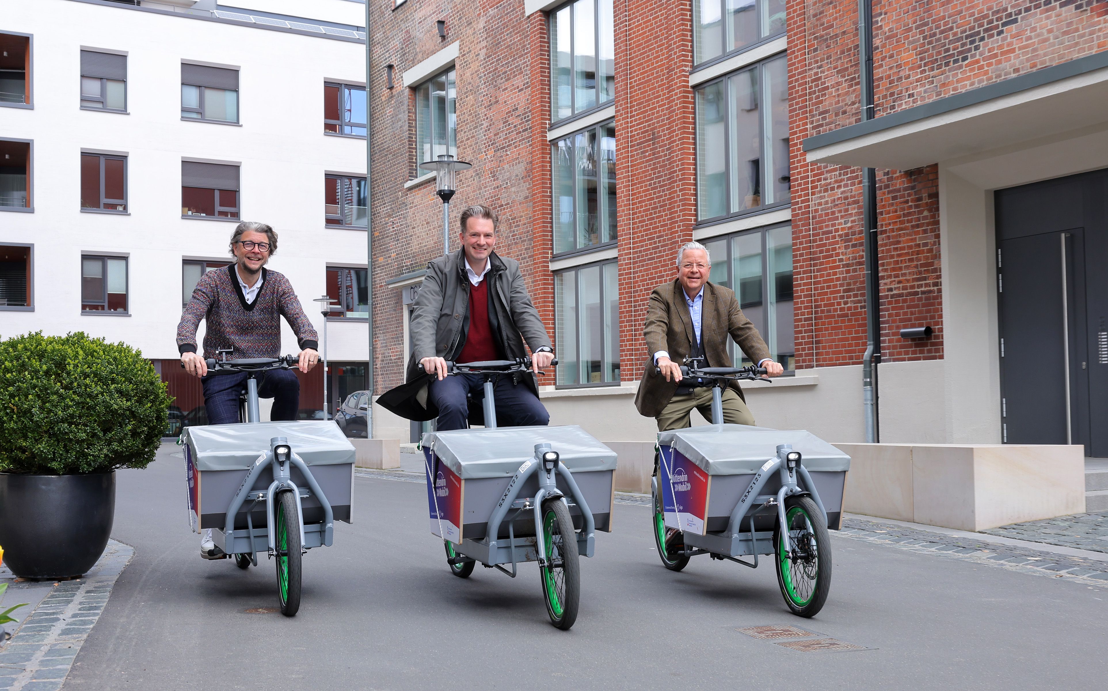 Machen auf den neuen E-Lastenrädern eine Rundfahrt ums MartiniTor in Kassel: NHW-Geschäftsführer Dr. Constantin Westphal, Kassels Oberbürgermeister Dr. Sven Schoeller und sigo-Geschäftsführer Kai von Borck.