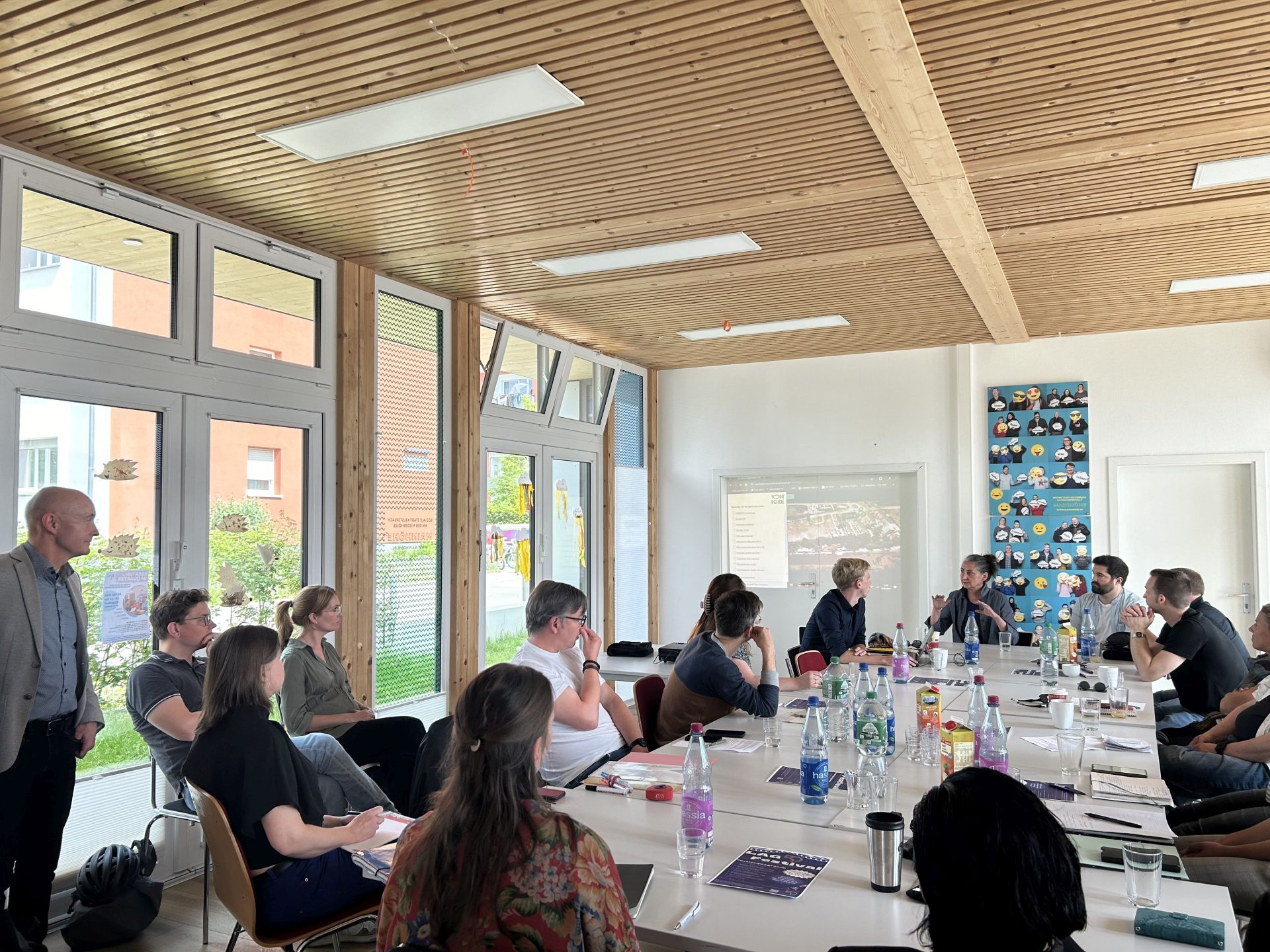 Eine Gruppe von Menschen sitzt an einem Tisch beisammen und diskutiert miteinander.