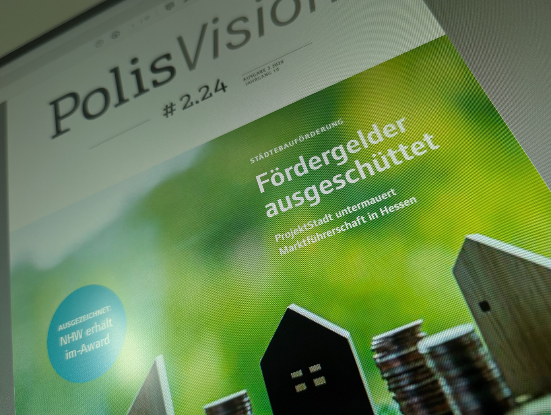 Ein Bild des Covers der neuen PolisVision auf der kleine Häuser vor einem grünen Hintergrund zu sehen sind.