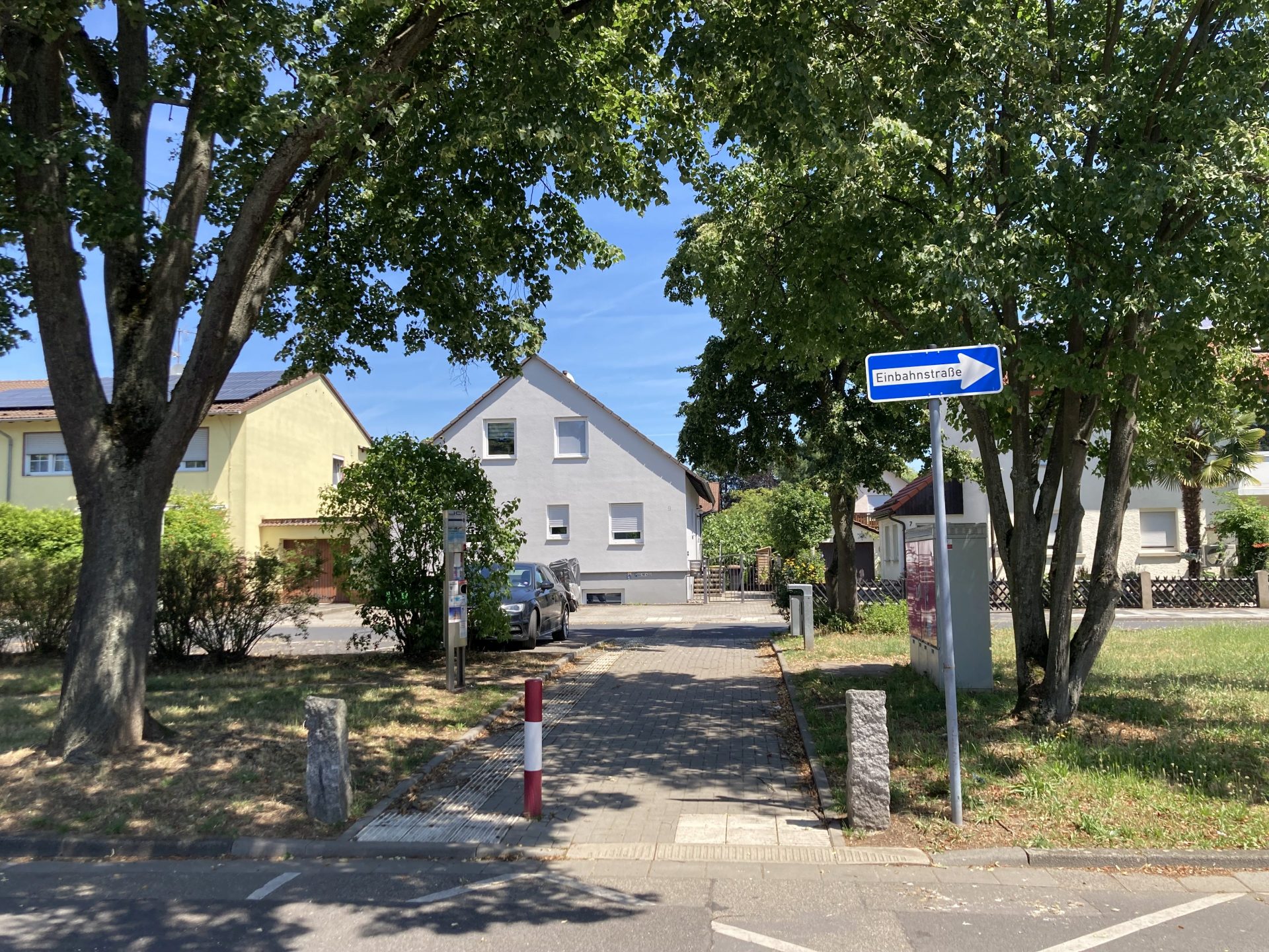 Grünstreifen in einem Wohngebiet mit Durchgang und Einbahnstraßenschild