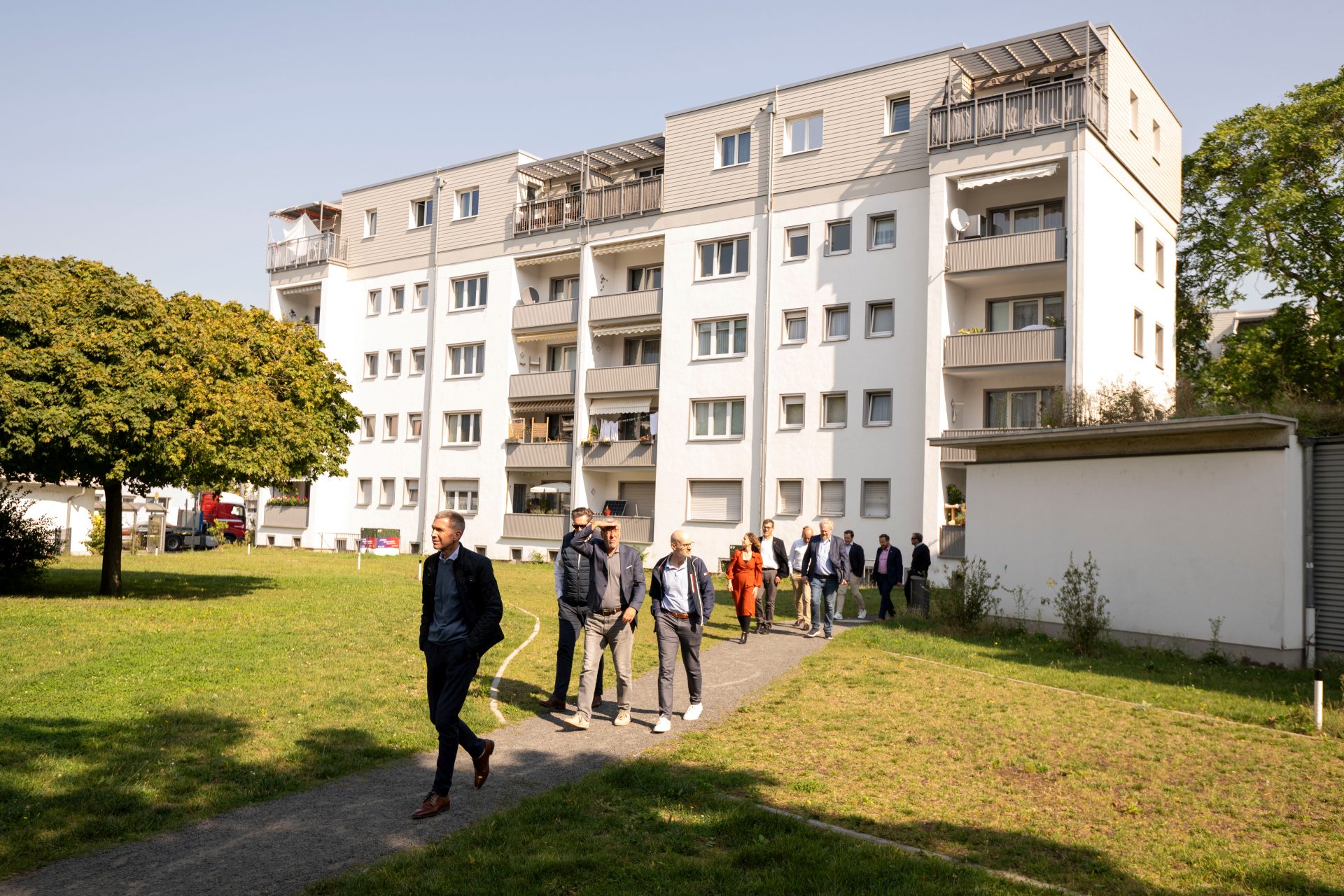 Eine Gruppe von Männern läuft über eine Wiese, im Hintergrund ein Mehrfamilienhaus