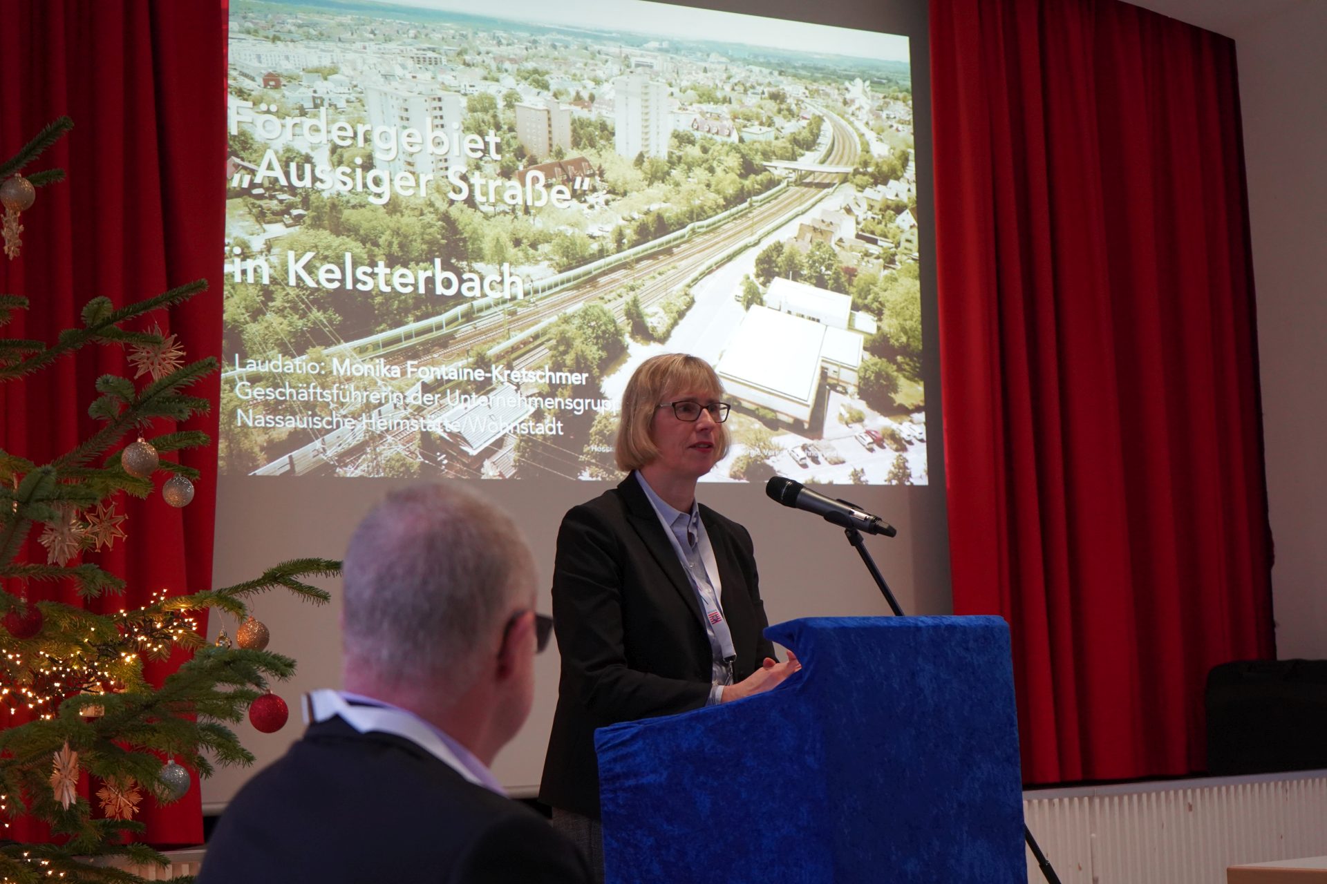 NHW-Geschäftsführerin Monika Fontaine-Kretschmer bei ihrer Laudatio für das Fördergebiet in Kelsterbach. Foto: Ministerium am Mikrofon