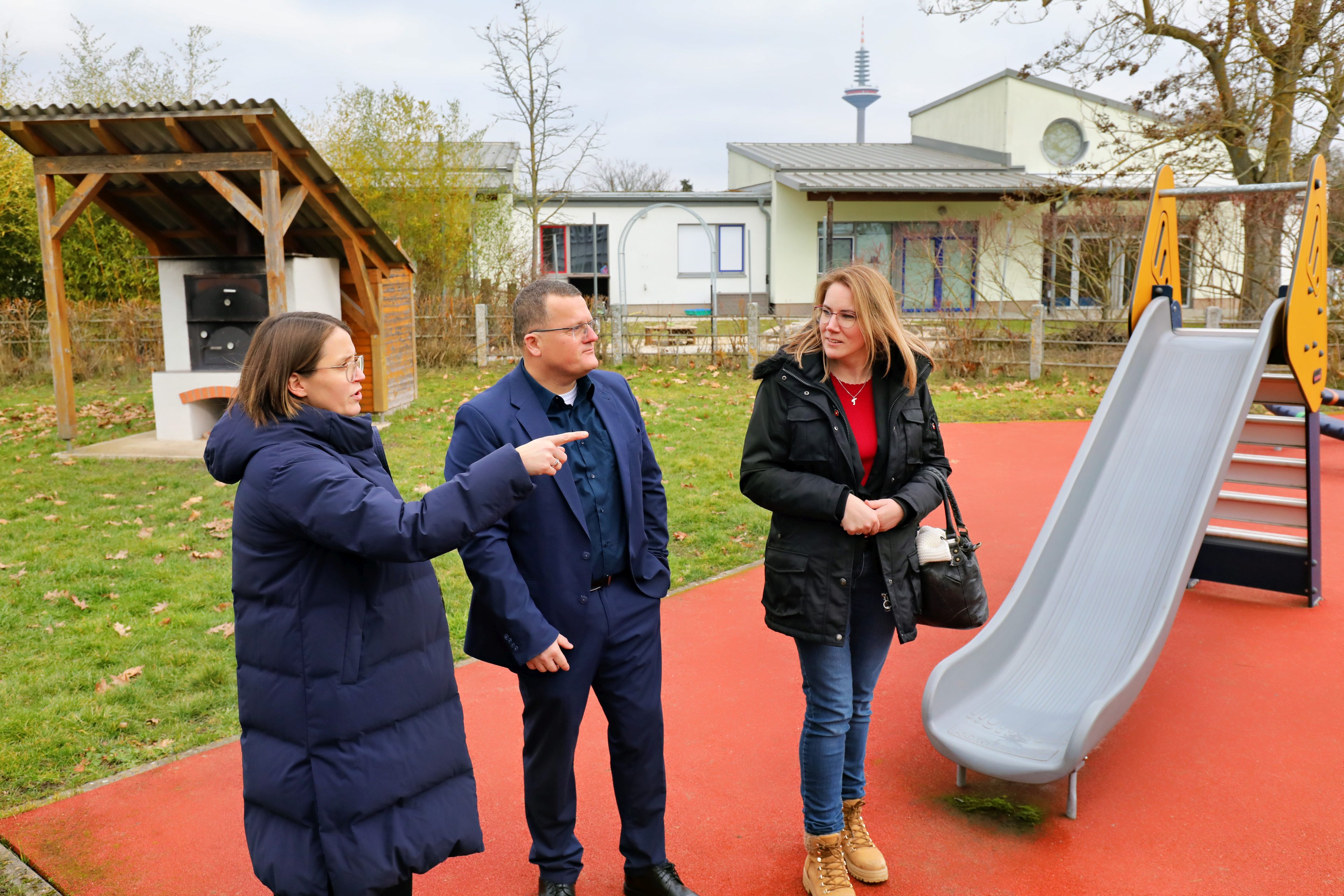 Lebenshilfe-Vorständin Dominique Deneu (li.) gab Regionalcenterleiter Holger Lack und Servicecenterleiterin Sina Jansohn bei einem Rundgang einen umfassenden Einblick in die Arbeit der Lebenshilfe Frankfurt.  Im Hintergrund eine Rutsche und ein Kita-Gebäude