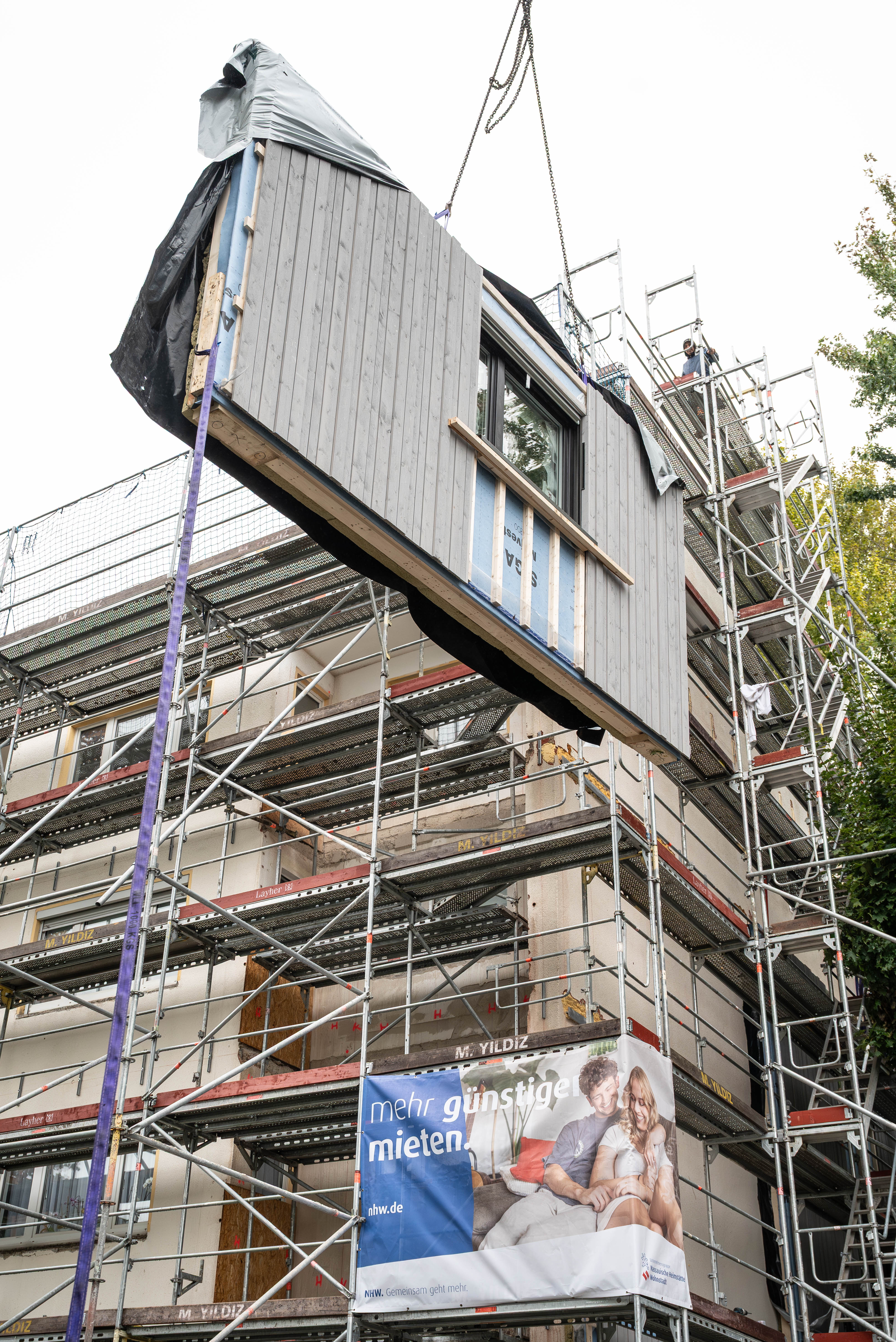 Ein Modul wird an die Fassade gehoben und eingepasst. 