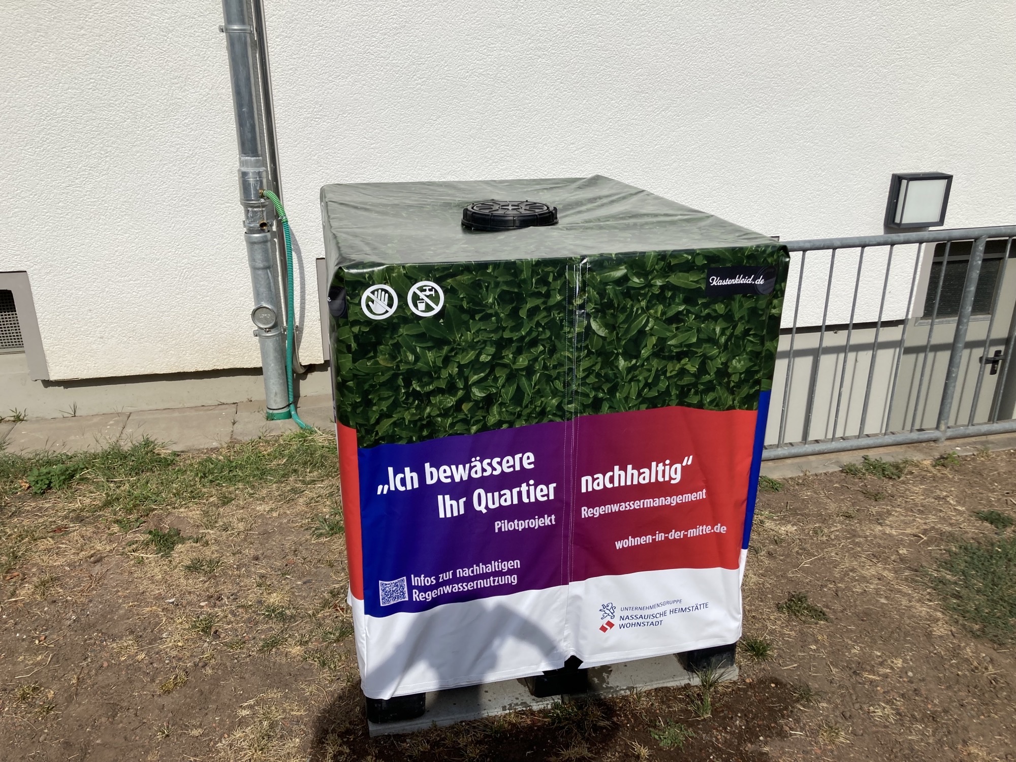 Eingehüllte Regentonne vor Hauswand