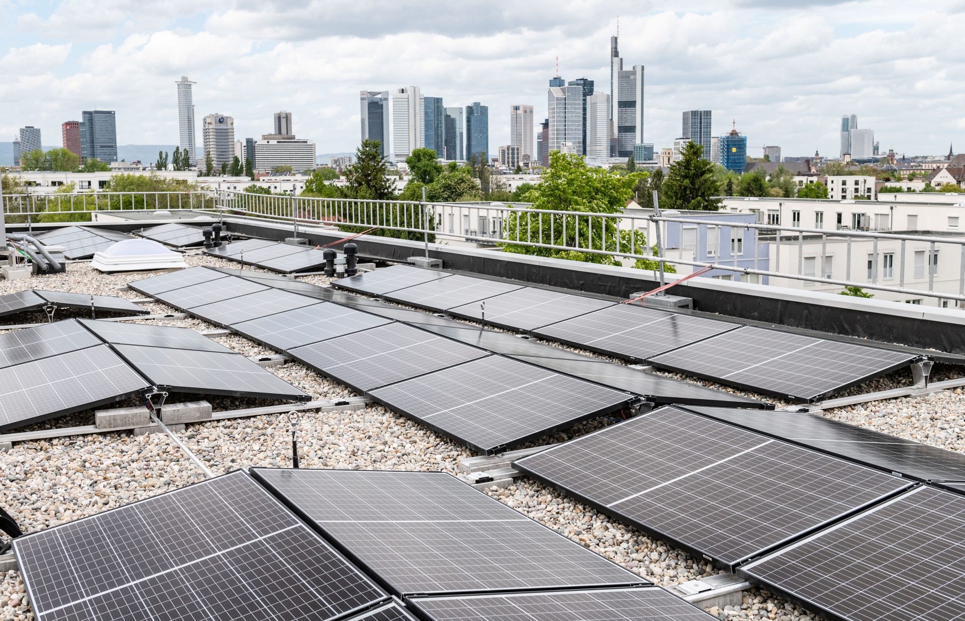 Photovoltaik-Anlagen auf den aufgestockten Dächern in der Fritz-Kissel-Siedlung. Im Hintergrund die Frankfurter Skyline.