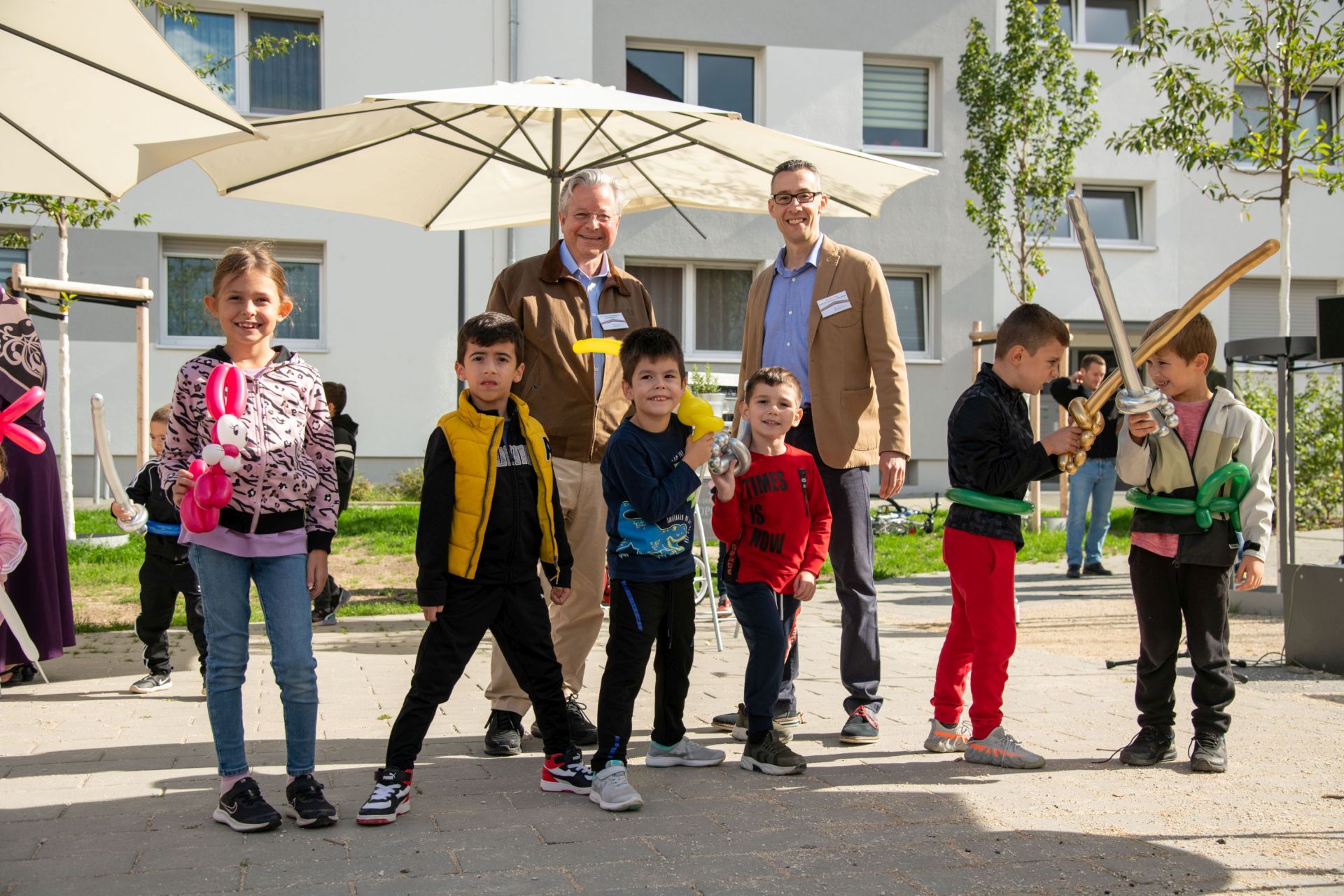 Foto von NHW-Geschäftsführer Dr. Constantin Westphal und Thomas Türkis, Leiter des NHW-Regionalcenters Wiesbaden mit Kindern beim Fest.