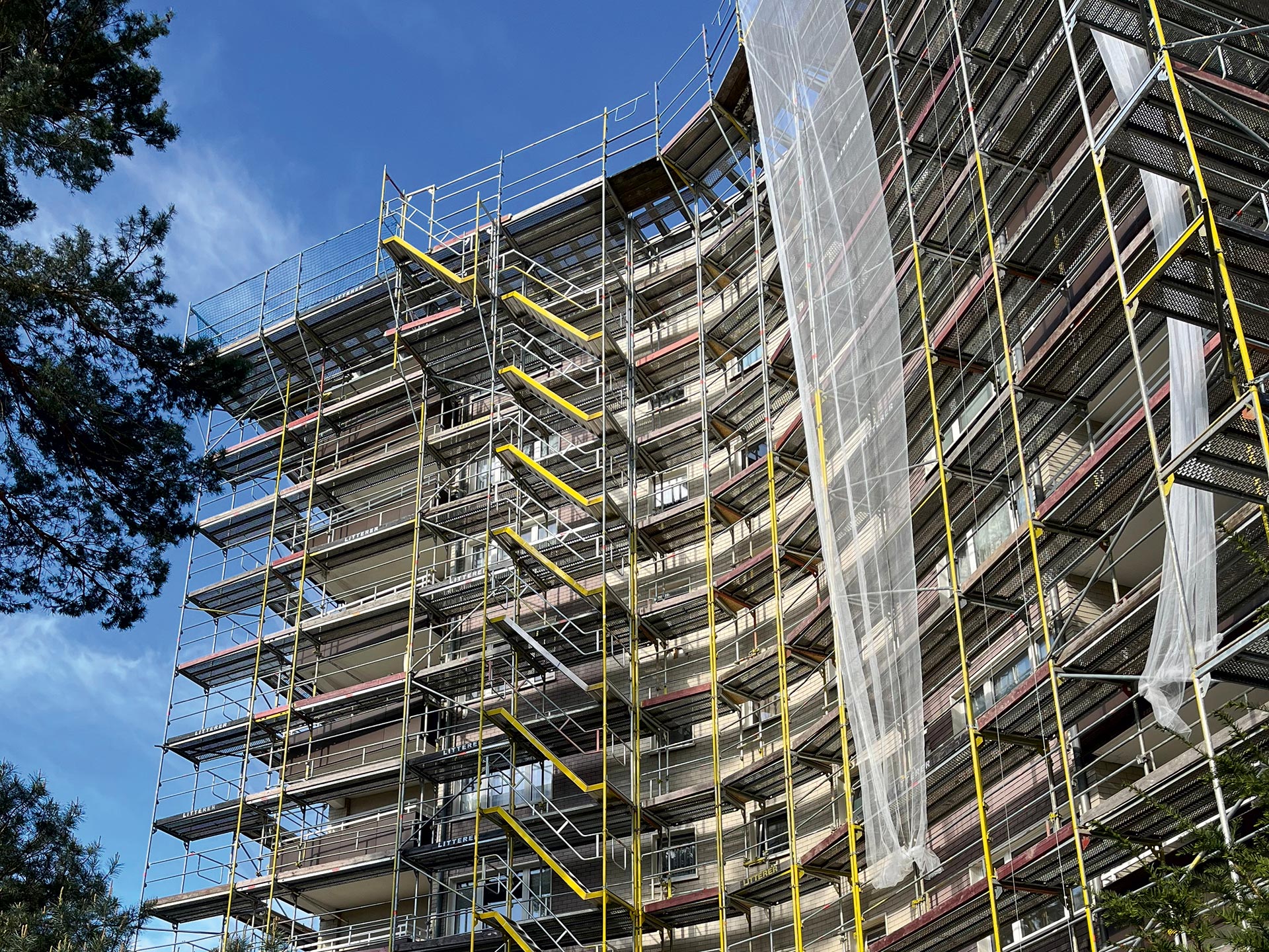 Ein hohes Wohngebäude, das in ein Gerüst gehüllt ist, von unten nach oben fotografiert.