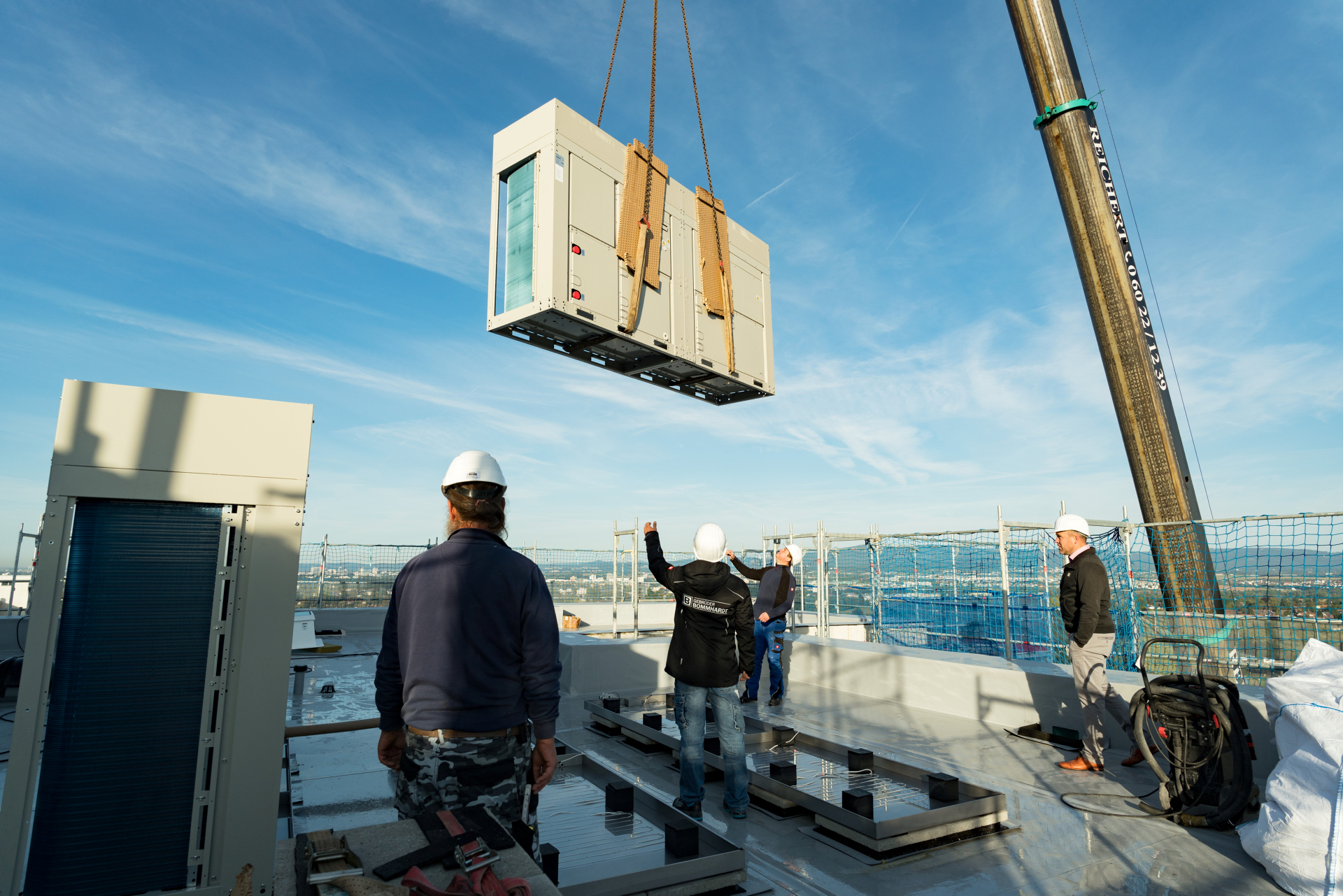 Eine Wärmepumpe wird an einem Kran auf ein Hausdach gehoben.