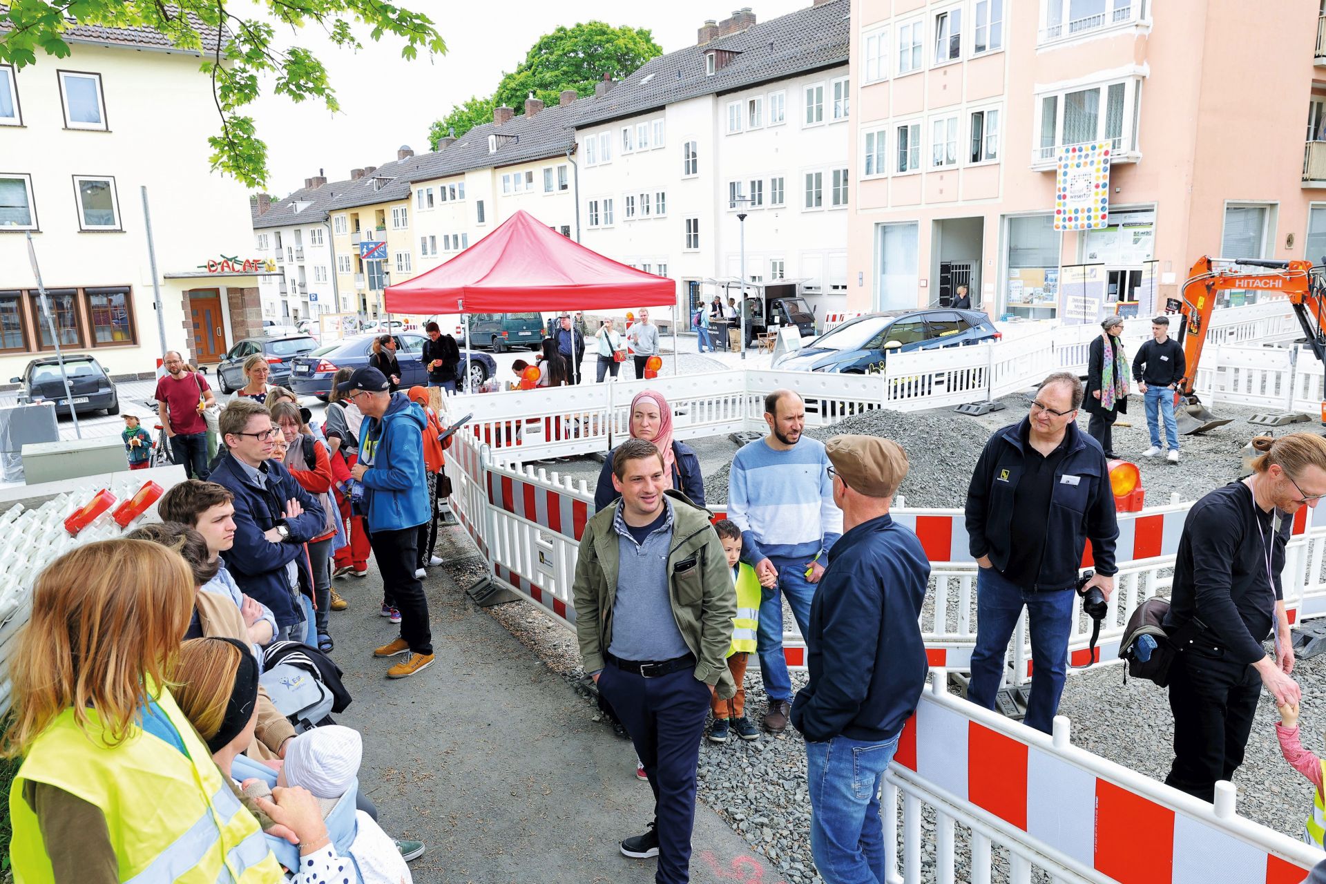 Eine Gruppe von Menschen steht binnen eine Baustelle auf einer Straße.