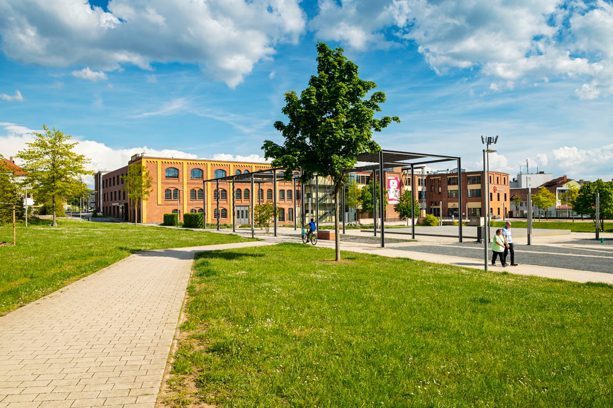 Grüne Wiese mit Fußweg, im Hintergrund altes Fabrikgebäude im Schilde-Park in Bad Hersfeld