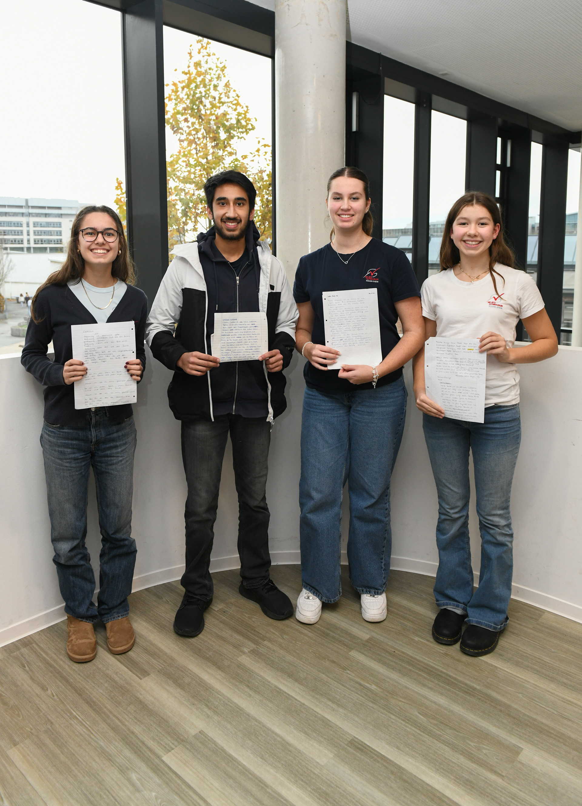 Vier junge Erwachsene halten stolz eine Urkunde in die Kamera.