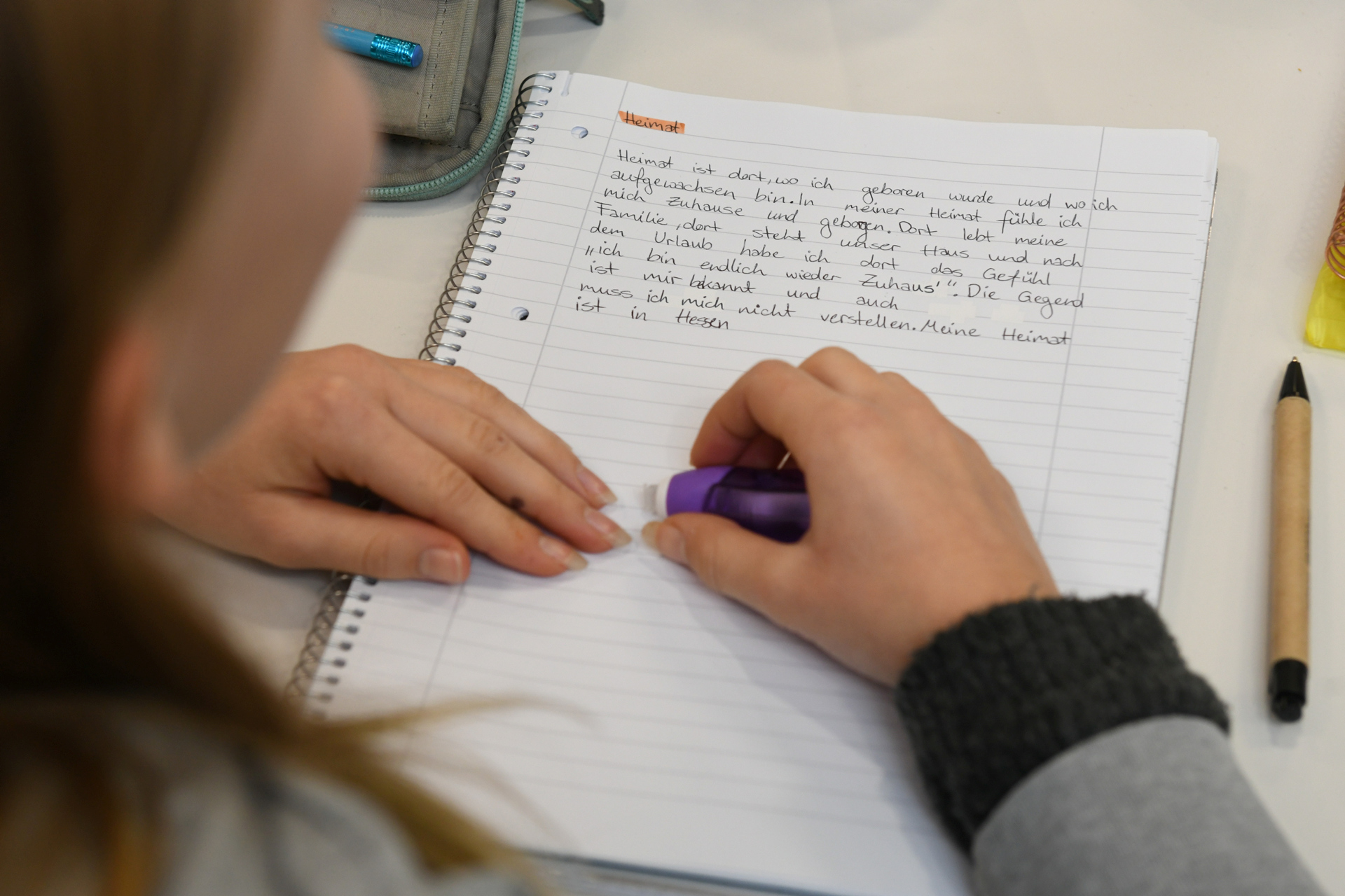 Blick über die Schulter eines Mädchens auf einen Schreibblock.