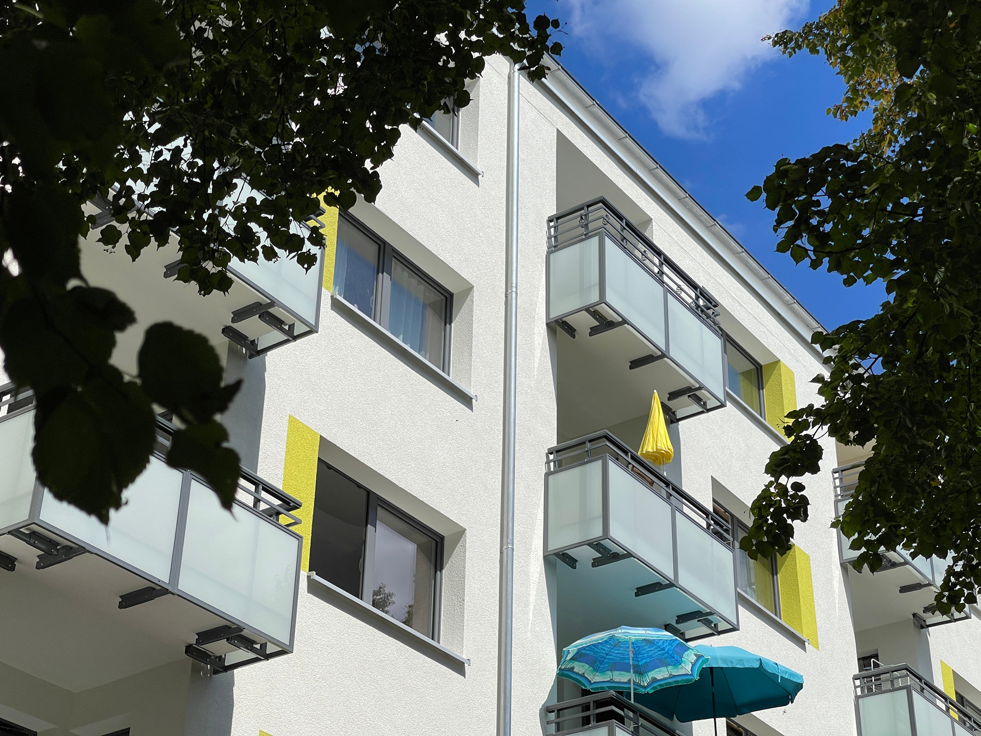 Ausschnitt von einem frisch gedämmten Balkon mit verglasten Balkonen und grünen Farbakzent am Fenster