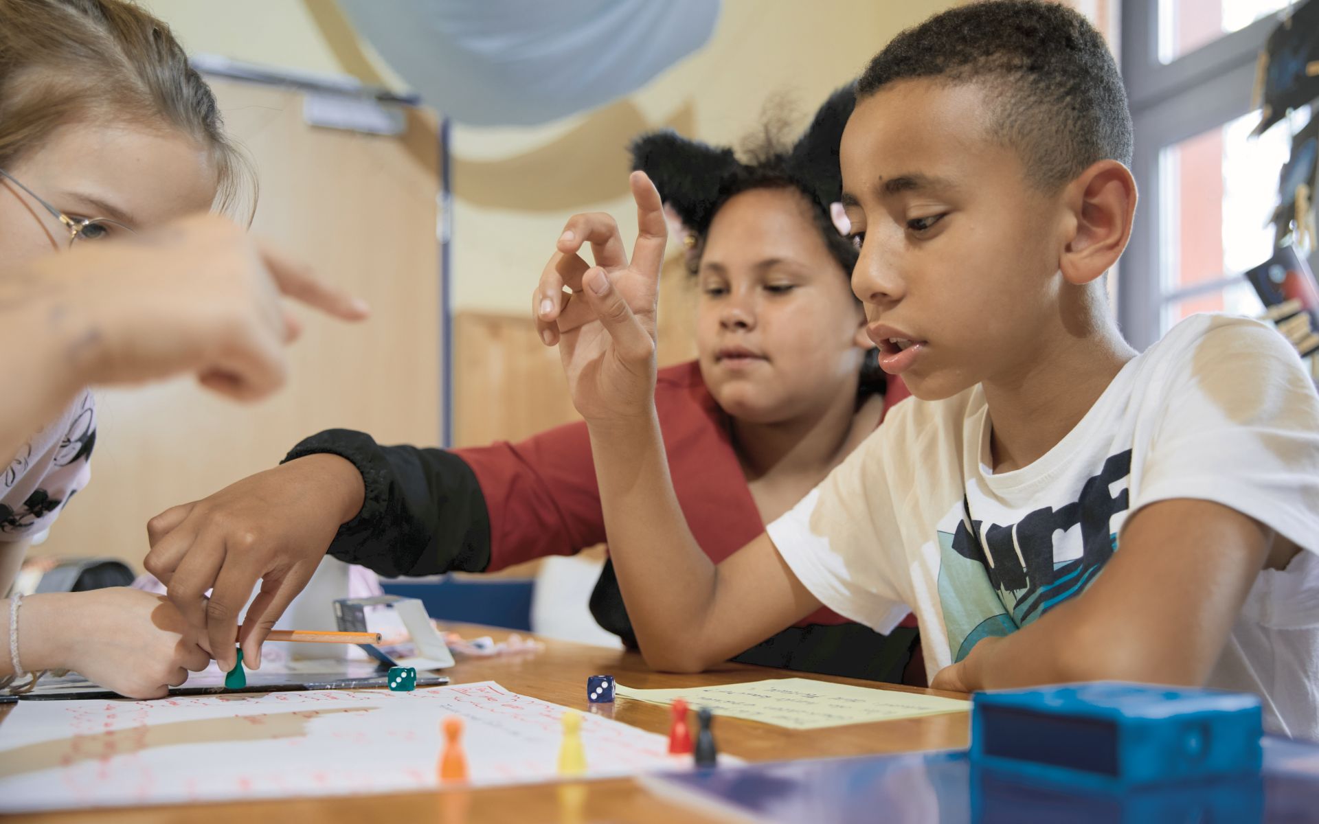 Drei Kinder an einem Tisch die zusammen etwas spielen