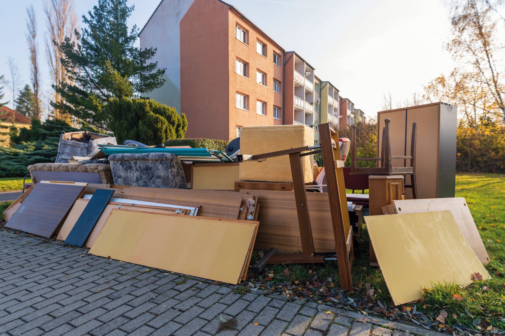 Sperrmüllablagerung im Vordergrund. Im Hintergrund ist ein Hochhaus