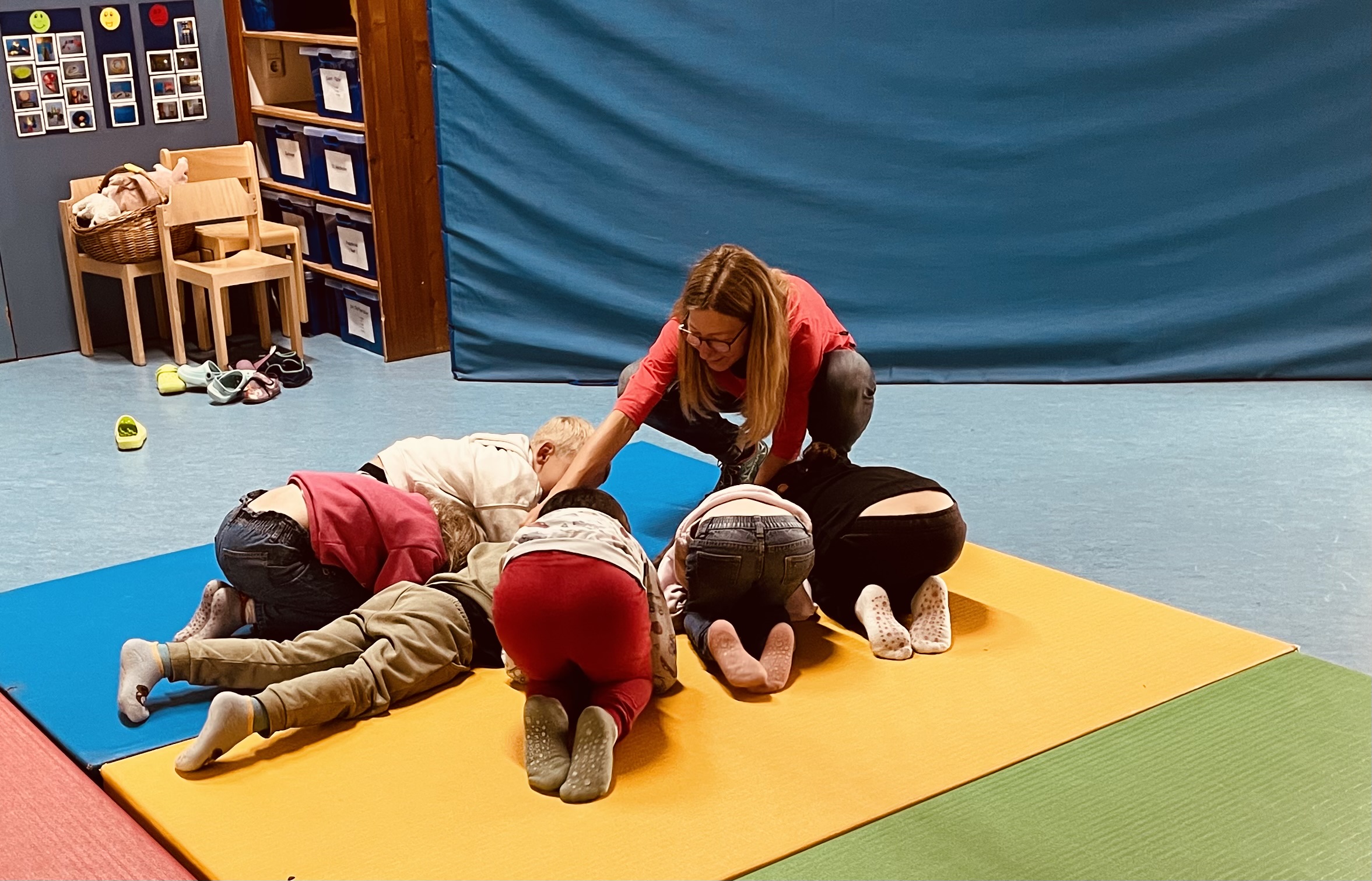 Kinder auf einer Turnmatte die Übungen machen