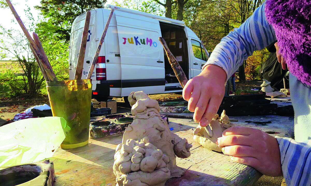 Im Hintergrund Sprinter-PKW und im Vordergrund Kind was bastelt