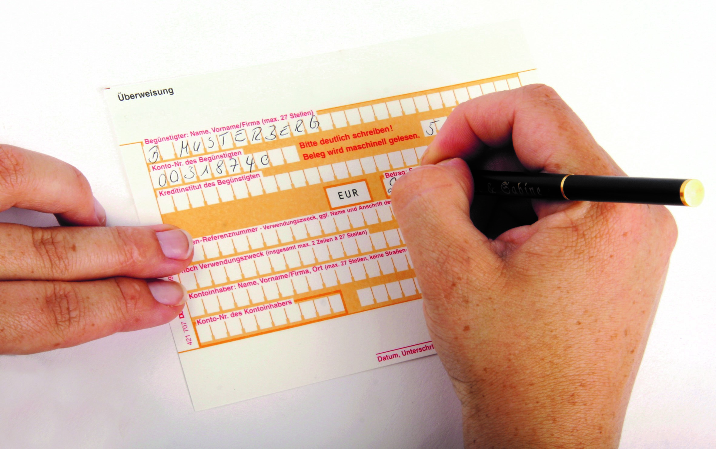Stockfoto von einem Überweisungsträger und einer Hand, die das Formular ausfüllt