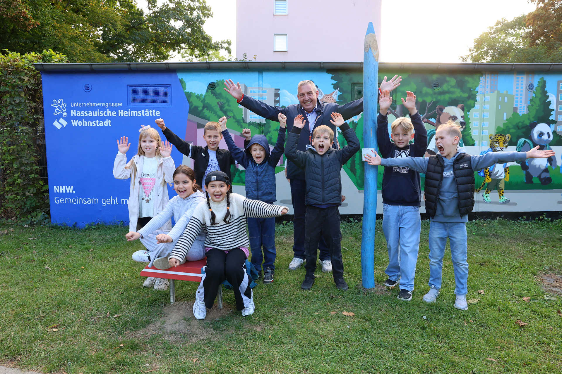 Gruppe von Jugendlichen vor einer gestalteten Garagenwand. Auf der Wand ist das NHW Logo zu sehen