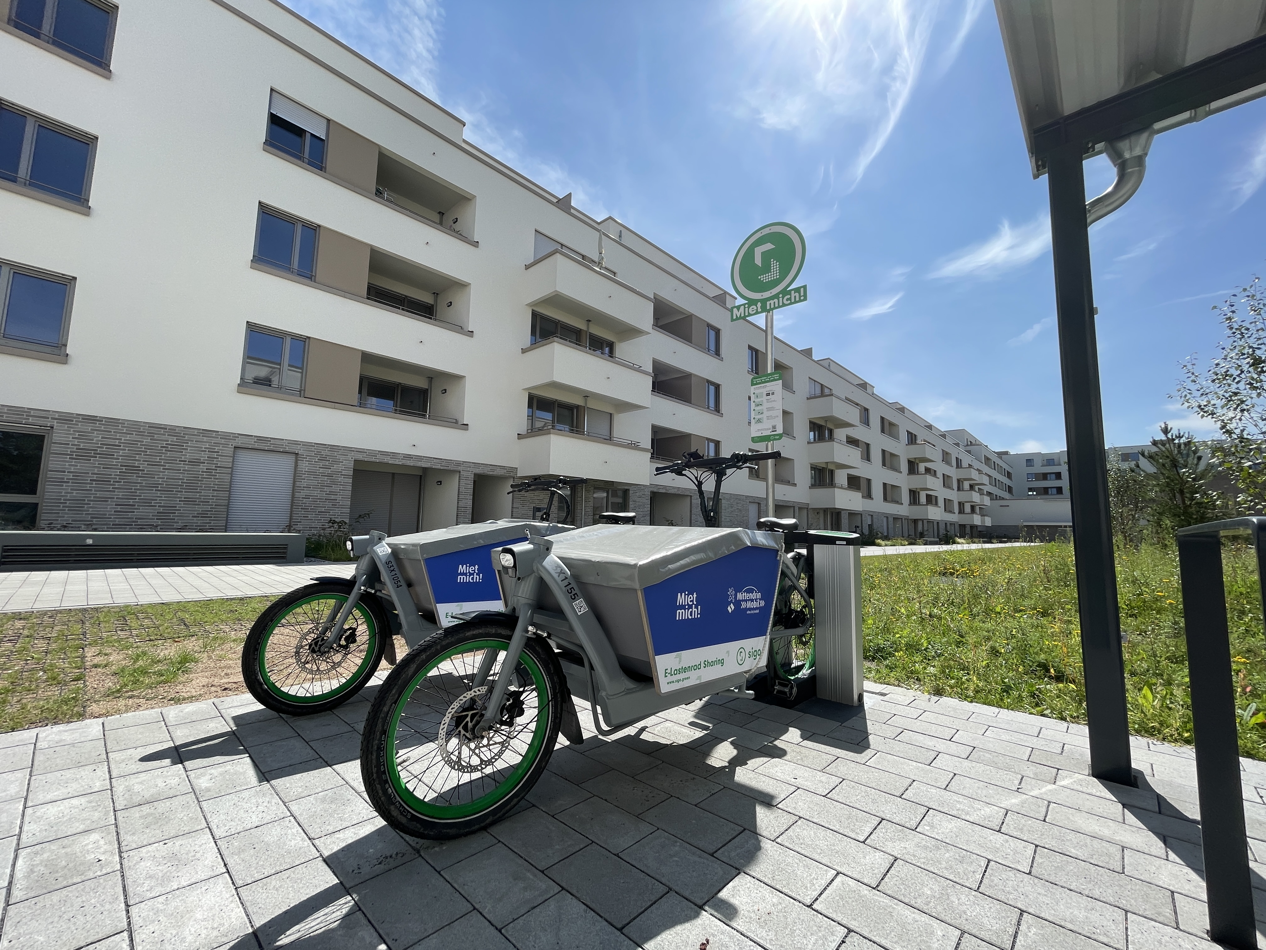 Zwei E-Lastenräder stehen vor einem Gebäude.